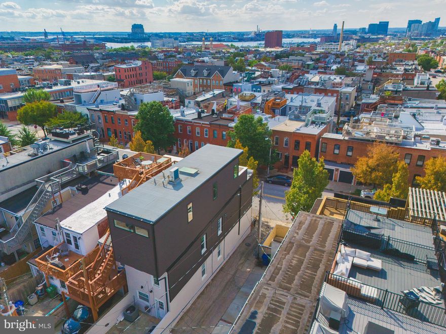 Welcome to 801 S. East Avenue, a beautifully remodeled Canton townhome offering the perfect blend of space, style, and Baltimore charm. This four-bedroom residence includes a fifth/flex room on the third level, currently used as a family room that showcases dramatic panoramic views of the downtown skyline and opens to a private rooftop deck—a perfect place for morning coffee, evening drinks, or small gatherings under the city lights.

The property has been thoughtfully reimagined, including the addition of an entire third floor, creating generous living space while preserving the character that makes Baltimore rowhomes so beloved. Inside, the home balances historic charm with modern finishes, featuring exposed brick, accent lighting, and a contemporary media wall with electric fireplace and custom built-in wood shelving.

Upon entering the main level, you’re greeted by a warm and inviting living room with ample natural light and open flow. A separate dining room connects to a tastefully updated kitchen with modern finishes, plenty of storage, and stainless-steel appliances. Just beyond the kitchen, a mudroom provides a practical transition to the rear of the home where you’ll find a full bathroom and access to an oversized parking pad—large enough to accommodate a full-size SUV, a rare and valuable feature in Canton.

The lower level runs the full length of the home and remains unfinished, offering exceptional storage potential or an opportunity for future expansion.

On the second level, you’ll find three bedrooms, including a bright and spacious front bedroom with tall windows and great natural light. Two additional modestly sized bedrooms and a renovated full bathroom (2023) complete this floor. Hardwood floors span the majority of the home, with carpet in select bedrooms for added comfort.

The third floor is truly a showpiece. It features the expansive primary suite with an updated ensuite bathroom boasting a skylight over the shower that floods the space with natural light. From the bedroom, you can even catch a glimpse of the iconic Natty Boh sign winking from across the city—a uniquely Baltimore view that never gets old. Also on this level is the fifth/flex room, currently used as a family room, offering sweeping skyline views and direct access to the rooftop deck. Whether you envision it as a media room, home office, guest space, or lounge, this level delivers flexibility and luxury.

Additional highlights include attic storage accessible from the upper level and a sump pump with French drain system for peace of mind.

Major updates and improvements:
    •    Roof – 2023
    •    Dual-zone HVAC: new electric heat pump & central air (third floor, 2023); new gas furnace & central air (first & second floors, 2021)
    •    Hot-water heater – 2019
    •    Bosch dishwasher – 2020
    •    Dimplex electric water vapor fireplace – 2019
    •    Carpet – 2023
    •    All-new second-floor bathroom – 2023
    •    Updated lighting and ceiling fans throughout

With three full bathrooms, four true bedrooms, and the flexibility of a fifth room or upper-level family space, this home offers rare versatility for the neighborhood. Every detail—from the thoughtful updates to the efficient systems—has been designed for comfort and convenience.

Located just steps from Canton Square, the waterfront, restaurants, coffee shops, and the best of city living, 801 S. East Avenue delivers the lifestyle you’ve been waiting for. Move right in and enjoy modern living with classic Baltimore character—a perfect combination in one of the city’s most sought-after neighborhoods.