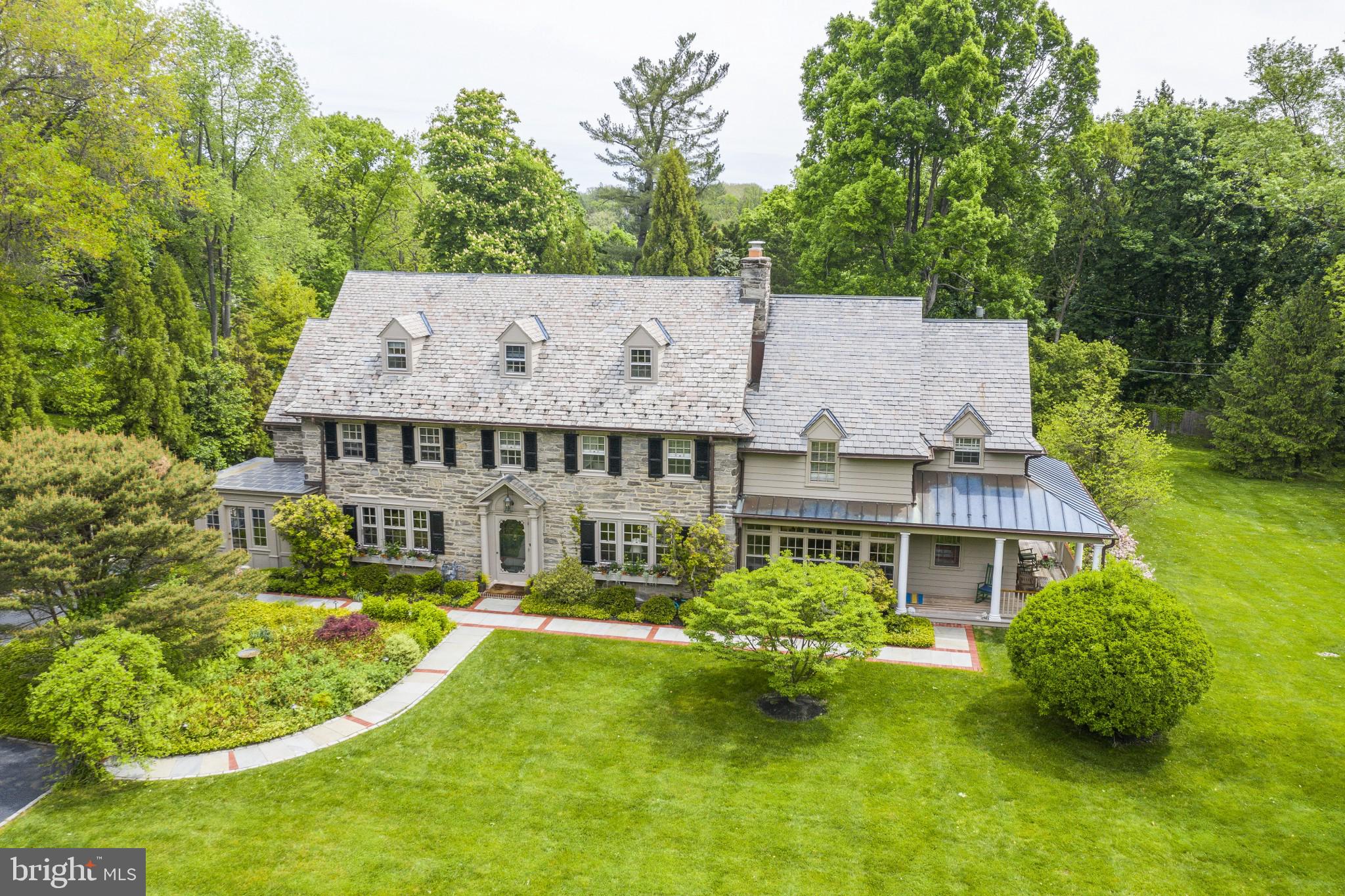Circa 1920, this spectacular stone manor home is nestled on a private 1.25 acre, flat lot with mature plantings, beautiful gardens, slate walkways, numerous porches and patios and a beautiful pool. A gardeners paradise offering privacy and numerous spots to entertain or sit back and relax with the bonus of easy accessibility to shopping, public transportation, all major routes and Lower Merion Schools. The craftsmanship and old world construction partnered with the extensive renovations and additions create a home with gracious and sophisticated living and entertaining spaces. With over 7,500 sq ft of living space, this home is finished with 7 bedrooms, 4 full and 2 half baths, highlighted with hardwood floors, high ceilings, detailed millwork, and built-ins throughout. Upon entering, the large front to back foyer provides access to a multitude of living spaces. The living room has beautiful windows, a gas fireplace, built-ins and flows through french doors into a large addition that houses a family room, private office, half bath and access to the side covered porch and yard. The beautiful sophisticated dining room is adjacent to a second private office and is nestled with the updated eat-in kitchen. The kitchen has a new stainless steel sink, a Bosch dishwasher, a Bosch double oven, SubZero refrigerator, an enormous working island with seating for 6+, the island is tiered to a Dacor 8 burner gas cooktop with built-in downdraft and spacious food prep area. There is ample storage with numerous pantry options, a wet bar and glass cabinetry with two Fisher Paykal drawer dishwashers to handle special glassware and entertaining as well as room for a family sized kitchen table. A second family room, off the kitchen, provides a sun filled entertaining space that faces the back yard, outdoor private shower, and pool. A separate pantry adjacent to this second family room houses a second refrigerator, stereo equipment and additional cabinetry. The second level has 5 large family sized bedrooms with large closets, two updated baths and laundry room. The peaceful master bedroom addition has high ceilings, architectural windows, walk in closets, private bath with shower and tub. The third level has two bedrooms, updated full bath and second laundry area. The lower level was completely renovated and includes a large mudroom with multiple closets, radiant heat in addition to a large finished room perfect for a pool table, bar and side room for a beverage refrigerator and wine storage. The unfinished area has the utilities, storage as well as exercise room. The attention to detail and care is evident throughout the home creating unique settings for entertaining as well as the living spaces any family desires. With Two separate Offices the ability to work from home could not be more convenient & allows for the flexibility needed in the current work/professional environment. The location is close to shopping, the airport and schools - with the bus stop at the end of the driveway! Numerous parks are close by - Ashbridge Park that has over 28 acres dedicated to playgrounds, running trails as well as tennis and sledding. Stoneleigh is right around the corner and has 42 acres available for exercise, picnics and horticulture. The combination of the private setting of the home with the accessibility of these amenities creates a perfect balance for today's family.