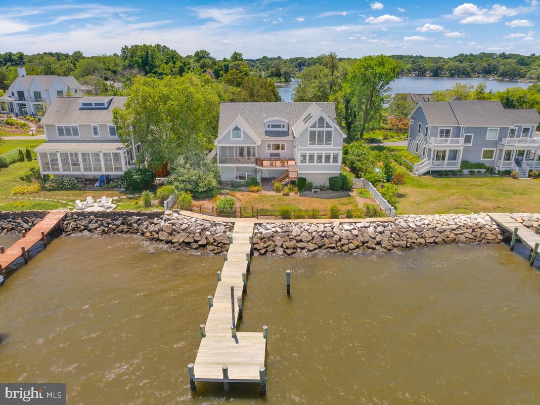 Coastal Cape Cod! Expansive water views of the Chesapeake Bay from this 3 bedroom, 2 bath charmer! Elevator access from garage level to main living level of the home. The open floor plan features water views from every room of the house. The kitchen boasts hardwood floors which extend in to the dining area with an electric fireplace and built in cabinets. Surrounded by windows, the large living room allows you to enjoy all of the activity on the bay and opens to the deck which leads down to the fenced water side yard. The primary suite has beautiful water views, full bath and opens to a lovely screened porch. 2 additional bedrooms on the main level share a full bath. There is a conveniently located main level laundry room. The upper level features a magnificent waterfront room with cathedral ceilings, skylights, window seats and a wall of windows that capture the beauty of the bay. There are 2 large walk in storage areas on the second level. A gate from the fenced rear yard opens to the 60ft. pier with one slip. The detached workshop is perfect for storing your outdoor needs. This is the perfect waterfront home for enjoying your summers or for year round living!
