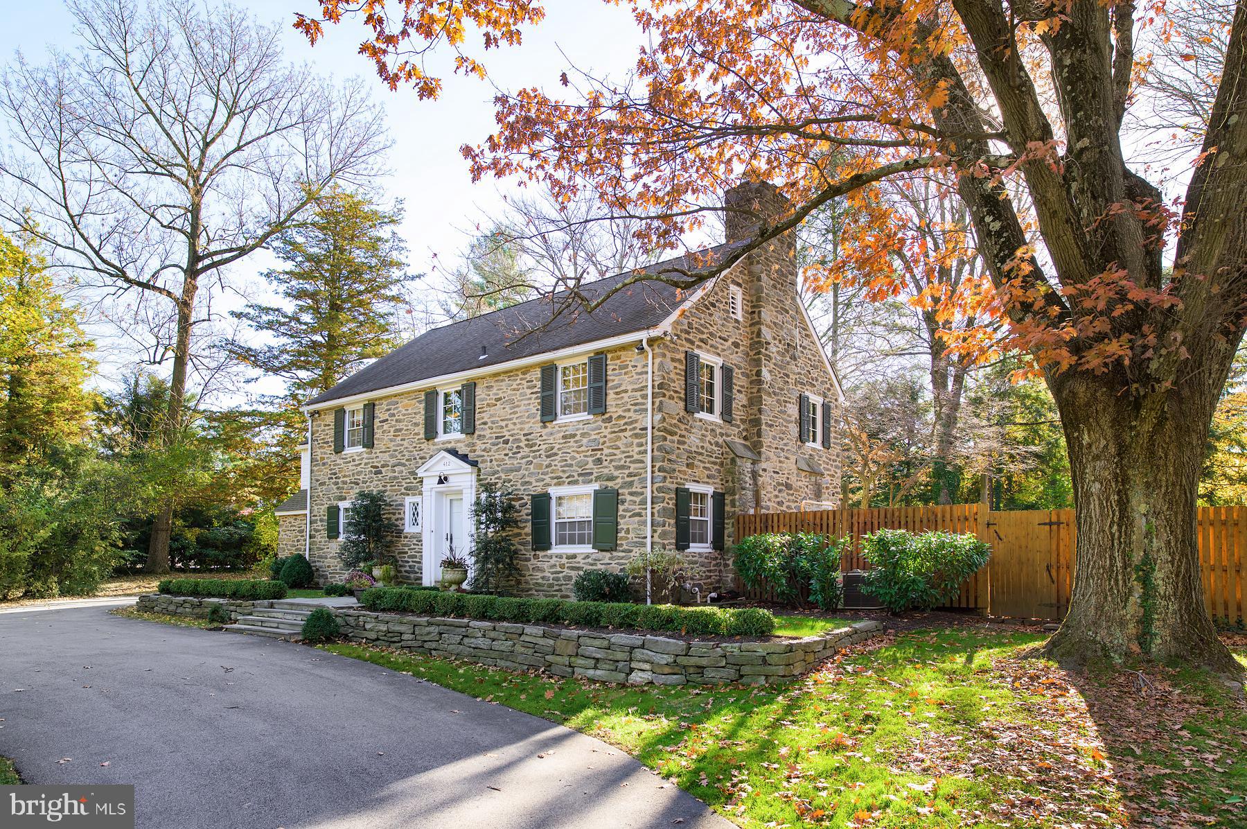 Elegant home conveniently located near schools, shopping, restaurants and the commuter train, yet nestled on nearly an acre of beautifully landscaped grounds featuring an inviting in-ground pool. This stone colonial with its stately curb appeal is THE Main Line classic you ll want to come home to! Enter the property through a charming gated driveway that leads to guest parking in the front or private parking in the 2 car, oversized garage in the back. A foyer with moldings, beautiful oak wood flooring, arched doorways and power room introduces you to the gracious stylings of this home. This level offers spaces for every day living and entertaining, alike. A generously proportioned LR with coffered ceiling, oak flooring, fireplace and built in bookcases opens to a stone patio. A private front office with bookshelves and fireplace is the perfect space to work from home or escape for some quiet time. The formal dining room is central to the level and offers plenty of space for everyday meals or holiday celebrations. A bonus space with built in desk, wet bar and wine refrigerator emphasizes the thoughtful use of space in this home. A large family room is open to the kitchen and features a built in entertainment center. The renovated gourmet kitchen features exposed wood beams, oak flooring, a center island with butcher block top, granite counter tops and stainless appliances. A charming corner fireplace makes this eat-in-kitchen a warm and cozy place despite its spaciousness! A door opens to the stone terrace to give this level a wonderful circular flow during warm months. Off the kitchen is a large mudroom with a back door to the driveway, access to the garage and private stairs leading up to the guest house/au pair quarters: a one bedroom suite with renovated full bath, kitchenette and living room. The 2nd level of the main house offers 5 bedrooms --4 of them en-suite with renovated baths and including a dramatic MBR with vaulted ceiling, views of the pool, customized walk in closets, cedar closet, and a lavish spa-like bath with double sink, soaking tub and oversized shower. A laundry room is located on this level for optimal convenience. A large landing serves as a bonus space for homework, reading or hanging out with friends. The lower level offers a finished game room with fireplace and full bath. An unfinished space provides yet another laundry room plus plenty of space for storage.