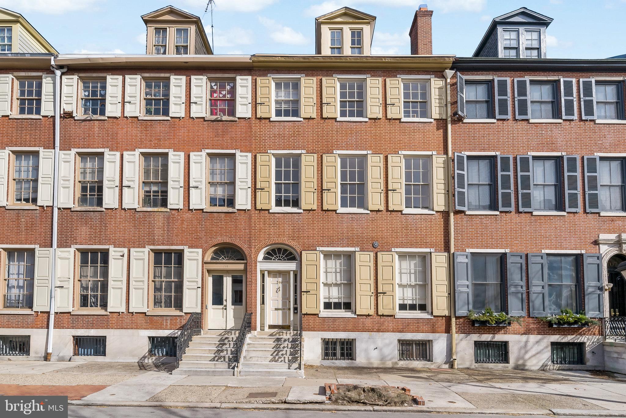 709 Pine Street is a large multi-family home situated in the prime location of Washington Square in the historic district of Philadelphia. Currently, the home has three units but has potential for expansion. Whether this home will be an investment for rental purposes, or a home of your own, it is worthwhile! This beautiful and historic home is complete with an oversized 4 car garage, easing your city-parking worries and providing outdoor access to each unit.
When entering the home through a grand front door, it leads you to the main foyer. To the right of the foyer is the first unit, with two bedrooms and two full bathrooms. When you walk through the door you are greeted by the living room which features 10+ feet high ceilings, large windows that drench the room with natural light, classic crown molding, and beautiful hardwood floors. The hardwood floors continue into the dining room, creating a nice flow from room to room. Continuing through the main floor brings you to the eat-in kitchen, with white cabinets, nice counterspace, and a sliding door pantry. There is a full bathroom off the kitchen with a large single sink vanity and a tub-shower combo. The first bedroom is spacious and features carpet floors, high ceilings, and a sliding door closet. Continuing down the long hallway you will find the Primary bedroom, which includes built-in cabinets, and a gas fireplace. The ensuite primary bathroom has a single sink vanity and a stall glass-door shower. A set of sliding glass doors lead to the back deck.
The lower level of the home can be converted to a fourth unit if desired, with its own entrance, three bedrooms and one full bathroom. It includes a finished recreational space that can be used for many purposes. It features a small bar with a sink and cooktop. The back room is currently being used as an office but could be used as an additional bedroom, gym, or whatever suits your needs. Two more bedrooms, one with an ensuite bathroom, and a bonus room/den are also found on the lower level.
Up the large staircases are the second and third units, which are practically identical, and include two bedrooms and two full bathrooms each. You walk through the front door and enter the large living room with soaring ceilings and the same gorgeous hardwood floors. An arched entry way opens to the dining room with large windows that face south and provide the room with warm natural light. Off the dining room is the galley kitchen with white cabinets and upgraded appliances. Down the long hallway is the first bedroom that features hardwood floors, a well-sized closet, and overhead lighting. There is a hallway bathroom with tile flooring, a linen closet, and a tub shower combo. Continuing down the hallway you will find the larger of the two bedrooms with the same hardwood floors and high ceilings. It features an ensuite bathroom with a single sink vanity and a stall shower. At the end of the hallway is a spacious laundry room with cabinetry for storage, counterspace, and a sink. This room provides access to the fire escape and the large deck.
Each unit has access to the large deck located above the garage, which provides wonderful city views and is a great space for entertaining guests. Located just minutes from Jefferson Hospital, Pennsylvania Hospital, and some of the city's best dining and entertainment, this property has so much offer!