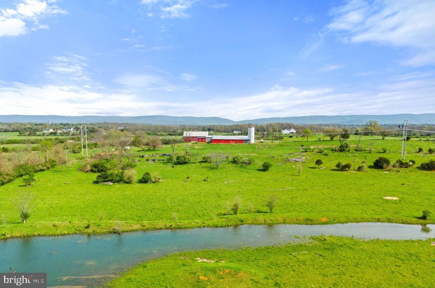 Blue Berry Hill Farm represents the agricultural heritage of the Shenandoah Valley while just 90 minutes from Washington DC. A total of 128 acres, this parcel is packed with opportunity and versatility. Superbly located in Clarke County with convenient Rt 50 frontage, the potential home site sits distantly back among pastures, atop a gradual elevation climb with expansive views of the Blue Ridge Mountains, farms, and country homes.  Currently a cattle grazing operation, it is thoughtfully laid out with three large, fenced pastures of 25-40 acres each surrounding the farmyard. A century-old Bank Barn stands as a sentinel over the land, solid, beautiful, and useful. The Upper level, built for hay storage with airflow and ventilation, adapts to social gatherings with friends and family; the exposed hand-hewn timbers provide a sense of rustic elegance. The lower level offers shelter to animals with three smaller adjoining paddocks. Across is a well-appointment 6-bay equipment building with three enclosed bays with tall roller doors, three open bays, concrete floors, air compressor system throughout, a welding room, a 500-gallon diesel tank and a two-post vehicle lift are ready for projects or hobbies. Ten wooded acres on the western edge is great for hunting and walks through the trails.  The land is protected by a VOF conservation easement and includes One unused DUR. Live the country life near historic estates like Long Branch, The Tuleyries, and Carter Hall. Play at the State Arboretum, Sky Meadows State Park, and the Shenandoah River—all within a 15-minute drive. Enjoy local restaurants, wineries, breweries, and golf courses with quick access to Rt 7 and I-81. Located 20 minutes from Winchester and Front Royal, 45 minutes from Middleburg, and just 90 minutes from Washington DC.