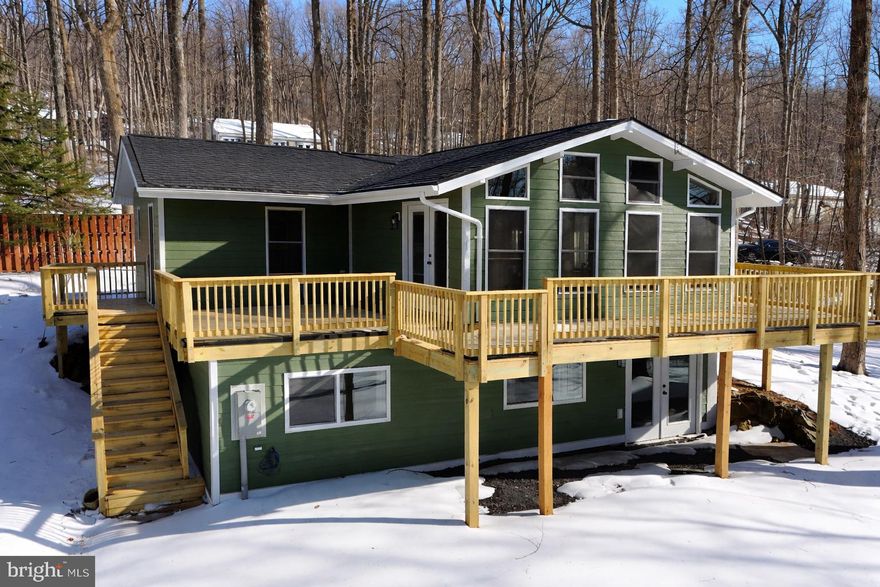 This beautifully renovated, move-in-ready chalet for under $450,000 is unlike anything on the market! Your own private mountain retreat has been tastefully renovated and is ready for its new owners to move-right in on day one!  Lots of higher end finishes including LP Smart Siding and other elevated touches throughout.  Nice flat lot, in an incredible commuter location privy to the wonderful amenities of Shenandoah Valley living, including: year-round lake access and within walking distance to a winery and vineyard with exceptional mountain views and a wildlife reserve! Spanning two finished levels, the home features three spacious bedrooms and three full bathrooms, making it an ideal choice for either a full-time residence or a serene weekend getaway. Located just minutes from I-66, the property provides the best of both worlds - a peaceful and serene setting surrounded by forests and beauty, as well as being less than an hour from the metro area.  The exterior of the home is designed to optimize outdoor living, highlighted by a show-stopping wrap-around deck that encompasses nearly the entire structure and flows into an expansive private patio perfect for entertaining.  Additional outdoor amenities include a lovely yard and a spacious covered carport. Inside, the gourmet kitchen is equipped with granite countertops, brand-new soft-close cabinetry, and stainless steel appliances.  A charming morning room sits adjacent to the kitchen, providing an appealing layout and nice flow from several different entrances.  The impressive great room features floor-to-ceiling windows to allow you continued enjoyment of the surroundings of nature both inside and outside. The primary suite serves as a private sanctuary, complete with a walk-in closet and a large en-suite bathroom.  Entire extra full bathroom near the great room (3 bathrooms total), adjacent to well-appointed office/sitting area.  An open stairway leads to the fully finished lower level, which offers a second living room with a walk-out to the grade-level yard, a large third large bedroom, and an additional full bathroom.  This property has so much to offer and is truly a great way to enjoy the best of the Blue Ridge. Agent/Owner