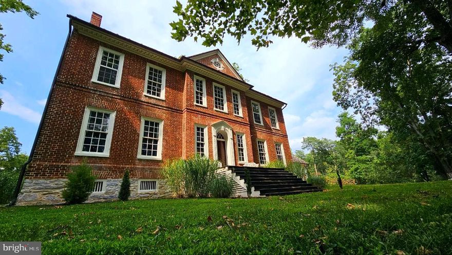 The Robert Worthington, Piedmont House - Complete with old-world craftmanship, modern amenities, stunning natural beauty, and endless possibilities for the future. Whether you’re seeking a family home, event venue, or a private retreat, this property provides a one-of-a-kind experience that seamlessly blends past with present. With its rich history and incredible location, the Piedmont House is truly a gem waiting to be re-discovered. 
Piedmont has been documented numerous times by historians as the most exquisite example of Georgian architecture in the state.  Sitting upon 29.08 serene acres just 1.5 miles from downtown Charles Town and 68 miles from Washington, D.C. Set back a ¼ mile off the main road, privacy is paramount, as the residence sits amidst ample woods, farmland, and rolling hills alike.
In around 1730, Robert Worthington obtained a grant from the Crown of England to settle in what was, at the time, Virginia. He completed the earlier house in 1735. This rustic, limestone portion of the home has an updated kitchen, bathroom, and bedroom suite with private entrance as well as direct access to the main house, perfect for a rental or in-law suite. The adjoined brick mansion was later built by Dr. John Briscoe in 1785. The home remained in the Briscoe family for centuries before being passed on to few other caretakers, including the late Jim Lehrer of PBS. 
Thoughtful improvements have been made over the years to blend historical significance with modern comforts. There have been upgrades to the central heating and cooling, electrical, and plumbing throughout. The two kitchens' feature granite and butcher block countertops, and new appliances and cabinetry. There have been updates to all of the bathrooms, the 3rd floor has been converted into a library, and a custom wine cellar featuring ebony marble flooring has been added to the basement level. The home features gorgeous original heart pine wood floors and millwork throughout, as well as a fireplace in every room.  
From the formal sitting room, featuring some of the earliest examples of wallpaper in America, to the master bath suite with copper soaking tub and fireplace, each room is a unique experience to be had.  The main floor features an expansive central hall with 12’ ceilings, a dine-in kitchen, a formal dining room with access to the garden, a sitting room, and a living room. Ascend the main stairs and you will find a bright and airy 25’ x 11’ living area adjoining the master and secondary bedrooms with 2 full baths. Upon reaching the third floor, you will find a cozy library with electric fireplace. The basement exhibits a finished entry way leading to the wine cellar, accompanied by ample unfinished storage spaces.
Step outside and you'll discover the 30' x 10' chicken coop and run (complete with 7 mature laying hens and 1 wild turkey friend), a fenced vegetable and herb garden, a full tennis court, fire pit, and riverside benches. There are multiple out-buildings including a large barn with finished floor, detached two-car garage, smoke house with electricity, pump house, and a derelict house far back on the property with lots of potential. 
The versatility of this estate is one of its greatest assets. Whether you are looking to create a homestead for your family or an event venue for weddings and celebrations, the Piedmont house offers the perfect setting. Alternatively, for those seeking a quieter lifestyle, the property’s unique location provides the perfect sanctuary. The expansive property allows for the cultivation of gardens, raising livestock, and keeping horses. With its serene setting, thoughtful design, and connection to the natural world, the Piedmont property offers an exceptional opportunity to live a life of peace and luxury amidst a piece of early American history. 
Ecological relevance: The land is diverse in plant and animal life. There is a relationship with nature conservancy to preserve this important habitat.