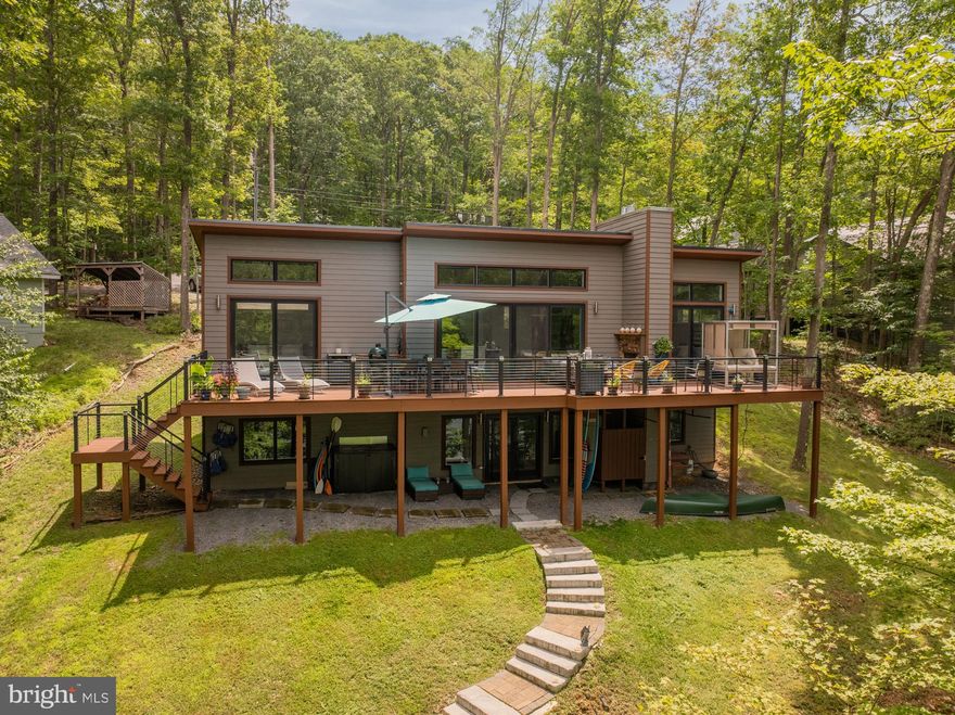 Exquisite one of a kind contemporary tucked away on sought after Lake Shore Drive.  128 feet of lake frontage on quiet Bee Tree Hollow Cove, with 20-foot-deep water depths off spacious Type A dock and total privacy.  Perched high above the cove “The Birdhouse” offers expansive four-season views from every window.  The property was thoughtfully designed and planned by current owners and local architect Douglas Storck with DCL Design Studio in 2018.  The home was completed in January of 2020 and features unique and custom finishes throughout.  The main level features a welcoming entrance, living room with modern gas fireplace, 12-foot vaulted ceilings, recessed lighting, durable hardwood floors and walls of windows on each side of the home allowing for picture perfect views throughout the morning, afternoon and evening.  A nature lover’s paradise!  Open concept kitchen with white cabinetry, Kitchen Aid appliances, quartz countertops, glass backsplash, stainless steel farm sink, beverage area with wine refrigerator and a built-in spice rack for the most discerning culinary enthusiasts.  The primary bedroom features a second gas fireplace, walk in closet and a luxury ensuite primary bath with copper tub and separate rain shower.  The second bedroom on the main level offers a second quiet retreat/suite with a second full bath off the kitchen.  A beautiful feature of the main level are three large sets of Andersen sliding glass doors and transom windows that step out to a glorious deck complete with a third outdoor gas fireplace and plenty of room for dining, entertaining, grilling, sunsets and bird watching.   The lower level of the home features a relaxing family room area with a third bedroom, third full bath and plenty of room for lakeside fun, games and recreation.  The lower level also features high ceilings, durable and modern flooring, recessed lighting and a convenient laundry area with custom barn doors.  Step outside and enjoy the secluded outdoor jetted shower and views (also prepped for hot tub)! This property is truly turnkey and ready for immediate enjoyment.  Other noteworthy features include a maintenance free metal roof with snow guards, foundation surround drainage system, tankless hot water heater, sprinkler system throughout, $50,000 rip rap, firepit and stairs to lake installation (2022) and expanded driveway with turn around.  The two properties that flank “The Birdhouse” are privately owned and not utilized as rental properties assuring quiet neighbors and privacy on both sides.   The home will be delivered fully furnished with high end designer furnishings, plentiful amenities and linens, kayaks, paddle boards, canoe, life jackets and more.