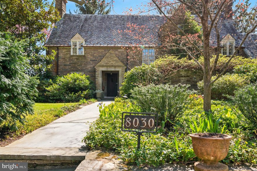 Welcome to 8030 Navajo Street, a rare and elegant stone Cotswold home designed in 1931 by renowned architect Robert McGoodwin. Nestled on a serene, tree-lined block in the heart of Chestnut Hill, this light-filled residence beautifully blends timeless architectural charm with thoughtful modern updates. A blue stone pathway guides you past blooming dogwoods to the handcrafted front door, adorned with custom ironwork, and into the gracious foyer. You'll find conveniently located powder room here with in-floor radiant heat.

To your left, the formal living room invites you in with a wood-burning fireplace and stunning custom built-ins. Pass under the archway that leads to an elegant dining room where show stopping garden views with lush seasonal foliage provide a picturesque backdrop for every meal. The adjacent cook’s kitchen, outfitted with top-of-the-line Miele appliances, opens to a delightful greenhouse—perfect for cultivating herbs and greenery year-round.

Upstairs, you'll find a primary suite overlooking the backyard, an en-suite bathroom also with in-floor radiant heat, and walk-in closet. Two more generously sized bedrooms round out this floor, both with en-suite bathrooms. Hidden behind an unassuming door you'll find a secret room above the garage, perfect for a home office, guest space, yoga retreat, etc..

Going up one more flight of stairs you'll find the attic currently being used as an artist's studio but there are many possibilities for this space. 

The fenced backyard is beautifully landscaped for year-round blooms with espaliered pear and apple trees, flowering dogwood, lilacs, evergreen magnolias, and a curated perennial garden—perfect for entertaining or quiet mornings outdoors. 

In an unparalleled Chestnut Hill location, the home is steps from Pastorius Park and a short stroll to the shops, restaurants, and cafés along Germantown Avenue. You're also within walking distance to Springside Chestnut Hill Academy, the Philadelphia Cricket Club, the Saint Martins Lane SEPTA Station, and just beyond, the extensive network of hiking, biking, and horseback riding trails in the Wissahickon Valley Park.

This is a unique opportunity to own a beautifully maintained and truly exceptional home in one of Philadelphia’s most desirable neighborhoods on a truly magical street.