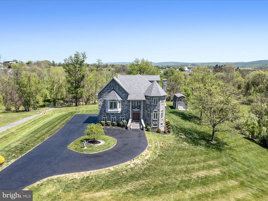 Tucked away in a quiet cul-de-sac in the sought-after Eastland community, this custom-built, stone-clad showstopper offers the perfect blend of luxury, space, and serenity. With 6 bedrooms, 3 full baths, 2 half baths, and 1.6 beautifully landscaped acres backing to mature trees and Evitts Run Creek, this home is a rare find.

From the moment you step inside, you’ll be struck by the oversized windows and timeless elegance of the interior with hardwood floors that run throughout the main and upper levels. The heart of the home is the expansive eat-in kitchen, featuring a massive center island, to gather and enjoy.  Eat-in  breakfast area, and walk-in butler’s pantry with laundry make this part of the house intimate and functional. Just off the kitchen, the formal living and dining rooms offer warm, inviting spaces for entertaining—anchored by a cozy wood-burning fireplace that adds charm and character.

Upstairs, the luxurious primary suite is a true retreat with two walk-in closets, a private balcony, a spa-inspired en suite bath with dual vanities, soaking tub, and tiled shower—plus a separate water closet for privacy and convenience. The next level offers four generously sized bedrooms, a shared full bath, and a loft-style family room with its own private balcony overlooking the creek. The top floor features a private fifth bedroom (currently used as an office, half bath, sauna, and full-size safe—both of which convey.

The fully finished walkout lower level is designed for versatility and comfort, with a large rec room (pool table conveys), sixth bedroom, full bath, and extensive storage space, all finished with durable LVP flooring.

Outdoor living is just as impressive. Relax beneath the rear patio pergola, explore the peaceful walking trails, or tinker in the two-story shed with built-in shelving. Enjoy year-round views of the creek, neighborhood pond, and distant Blue Ridge Mountains.

Built to last, this full stone exterior home includes a 5-zone HVAC system with individually baffled zones, a 2018 architectural shingle roof, and quality finishes throughout. Most furniture and the zero-turn mower are negotiable.

Located just minutes from Routes 340 and 7, this stunning home offers refined living with easy access to Virginia, Maryland, and all the charm of the Eastern Panhandle.