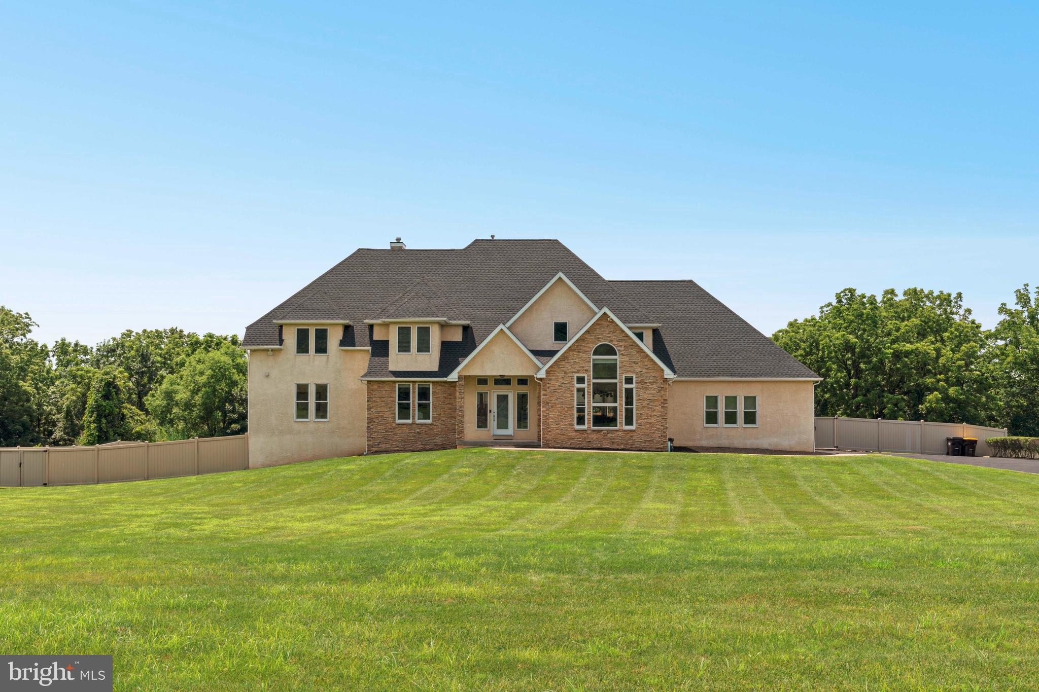 Welcome to a truly remarkable residence that blends timeless elegance with contemporary design, nestled in one of Bucks County’s most coveted locations. This custom-built estate offers over 4800 square feet of luxurious living space and sits on two beautifully landscaped acres backing to tranquil open space. Every inch of this meticulously maintained home exudes quality craftsmanship, thoughtful upgrades, and architectural sophistication.
As you enter through the grand double doors, you're greeted by a soaring two-story foyer with a graceful turned staircase, flanked by a sun drenched home office on one side and a refined living room on the other. Light oak hardwood floors flow effortlessly through the main living areas, enhancing the home’s open, airy ambiance.
At the heart of the home lies the stunning chef’s kitchen, a culinary showpiece featuring two oversized waterfall granite islands, high end appliances including a professional grade refrigerator, wine fridge, and ample custom cabinetry. A large breakfast area invites casual dining and flows seamlessly into the two-story family room, where a dramatic wall of windows floods the space with natural light. A sleek gas fireplace serves as a striking focal point, offering warmth and elegance to both the kitchen and family room.
A glass door lead from the breakfast area to a spacious composite deck that spans the rear of the home, offering panoramic views of the expansive fenced-in backyard. Step down to a spectacular travertine patio. Perfect for al fresco dining, backyard gatherings, or peaceful moments surrounded by nature.
The first floor primary suite is a serene sanctuary, designed with luxury and comfort in mind. Vaulted ceilings, a private fireplace, and direct access to the rear deck set the tone for indulgent living. The spa inspired en-suite bath features heated floors, a soaking tub, oversized walk-in shower, dual vanities, a private water closet, and an expansive dressing room with custom organization. A unique second floor closet sits above the suite, offering additional storage or the potential to be converted into another bedroom or private sitting area.
Upstairs, three spacious secondary bedrooms each offer their own en-suite bathrooms and generous closets, ensuring comfort and privacy for all. A conveniently located second-floor laundry closet adds everyday ease.
The fully finished walk-out lower level is an entertainer’s dream and a true extension of the home’s luxury. This level boasts an expansive recreation and media area, a full wet bar with granite countertops and a wine fridge, a separate full kitchen, a stylish full bathroom, a private guest or au pair bedroom, and a versatile bonus room perfect for a home gym, playroom, or studio. With direct access to the travertine patio, this space is ideal for extended family, visitors, or multi-generational living.
Additional features include radiant heated floors in every bathroom, three-car garage parking, a custom mudroom with built-ins, and extensive storage options throughout.
From its grand interior spaces to its thoughtfully designed outdoor living areas, this home truly offers everything, and more. Don't miss your chance to experience this one of a kind custom estate in the heart of Wrightstown.