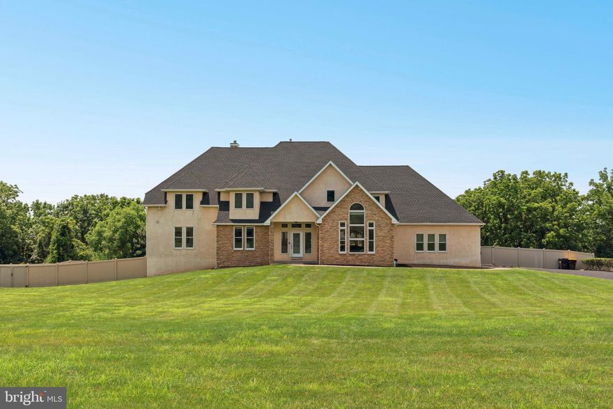Welcome to a truly remarkable residence that blends timeless elegance with contemporary design, nestled in one of Bucks County’s most coveted locations. This custom-built estate offers over 4800 square feet of luxurious living space and sits on two beautifully landscaped acres backing to tranquil open space. Every inch of this meticulously maintained home exudes quality craftsmanship, thoughtful upgrades, and architectural sophistication.

As you enter through the grand double doors, you're greeted by a soaring two-story foyer with a graceful turned staircase, flanked by a sun drenched home office on one side and a refined  living room on the other. Light oak hardwood floors flow effortlessly through the main living areas, enhancing the home’s open, airy ambiance.

At the heart of the home lies the stunning chef’s kitchen, a culinary showpiece featuring two oversized waterfall granite islands, high end appliances including a professional grade refrigerator, wine fridge, and ample custom cabinetry. A large breakfast area invites casual dining and flows seamlessly into the two-story family room, where a dramatic wall of windows floods the space with natural light. A sleek gas fireplace serves as a striking focal point, offering warmth and elegance to both the kitchen and family room.

A glass door lead from the breakfast area to a spacious composite deck that spans the rear of the home, offering panoramic views of the expansive fenced-in backyard. Step down to a spectacular travertine patio. Perfect for al fresco dining, backyard gatherings, or peaceful moments surrounded by nature.

The first floor primary suite is a serene sanctuary, designed with luxury and comfort in mind. Vaulted ceilings, a private fireplace, and direct access to the rear deck set the tone for indulgent living. The spa inspired en-suite bath features heated floors, a soaking tub, oversized walk-in shower, dual vanities, a private water closet, and an expansive dressing room with custom organization. A unique second floor closet sits above the suite, offering additional storage or the potential to be converted into another bedroom or private sitting area.

Upstairs, three spacious secondary bedrooms each offer their own en-suite bathrooms and generous closets, ensuring comfort and privacy for all. A conveniently located second-floor laundry closet adds everyday ease.

The fully finished walk-out lower level is an entertainer’s dream and a true extension of the home’s luxury. This level boasts an expansive recreation and media area, a full wet bar with granite countertops and a wine fridge, a separate full kitchen, a stylish full bathroom, a private guest or au pair bedroom, and a versatile bonus room perfect for a home gym, playroom, or studio. With direct access to the travertine patio, this space is ideal for extended family, visitors, or multi-generational living.

Additional features include radiant heated floors in every bathroom, three-car garage parking, a custom mudroom with built-ins, and extensive storage options throughout.

From its grand interior spaces to its thoughtfully designed outdoor living areas, this home truly offers everything, and more. Don't miss your chance to experience this one of a kind custom estate in the heart of Wrightstown.