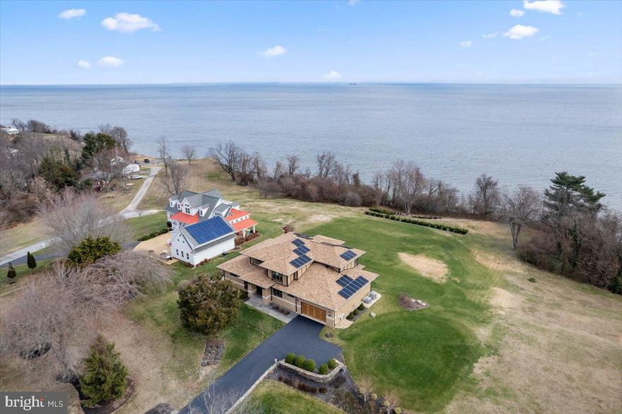 EXTRAORDINARY all brick Chesapeake coastal estate property in mid Calvert County is available now! This stunning home by Classic Design & Build evokes the Prairie style with spectacular custom cabinetry, trim, and exterior style. Located in a small but special community on an elevated lot with Bay views, this home delivers on quality, features and lifestyle…plus if you enjoy a beautiful lawn with irrigation, this will be an added bonus! Solar energy has been incorporated into the utility plan. The panels are owned/convey, and they save thousands in electric annually. Power agreement, recent bills are available for review!  Enter the home to 10ft ceilings and views of the bay. Swoon over the Brazilian cherry floors, the cherry stairway and custom railings. The heart of the home is a great room with stone front fireplace, gourmet kitchen + dining room, breakfast room. On the north wing bayside is the very large primary suite with dual closets and a luxurious owner’s bathroom. On the south wing bayside is an office/guest area with adjacent full bath. A unique central services hall with built-in bar/coffee station, mud room, laundry room, oversized garage with storage and shop space is a unique and desirable part of the design. The original site plan was drawn with an in-ground pool, and so the septic system was placed with that in mind. See documents. The beautiful upper level is perfection with 9’ ceilings, a second living room overlooking the Chesapeake Bay, two gracious suites and a third large corner bedroom with adjacent full bath. The lower level was finished in 2018, and it is a beautiful space with a very custom high end bar, private gym, third living room and a 5th bedroom with connecting full bath. Three levels of luxury. We cannot possibly say enough here…VISIT TODAY!