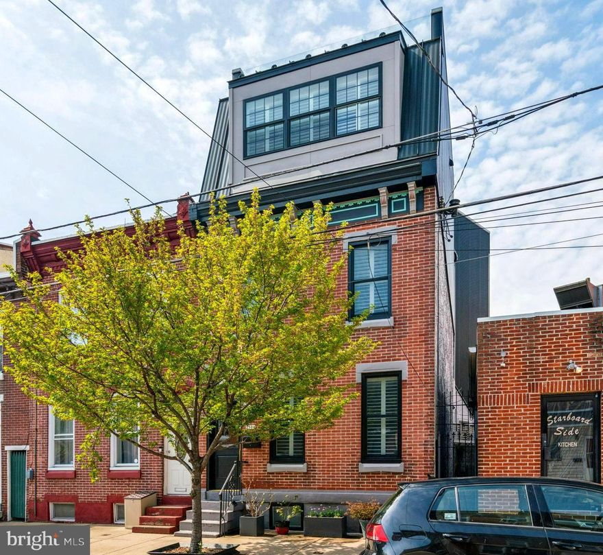 Incredible opportunity to own one of the most distinctive residences in the heart of Fishtown.  2504 E. Norris Street is now available.  This remarkable 4-bedroom, 2 full & 2 half bath home seamlessly blends historic charm with updated modern luxury, offering over 2,200 sq. ft. of thoughtfully designed living space, plus private parking, a fantastic roof deck and much more.  Originally built with character and craftsmanship, the home had previously underwent a transformative renovation, including a third-floor expansion and restoration of many original features.  Step inside through the preserved entry vestibule and be welcomed by detailed millwork and moldings, an original fireplace mantle, and high ceilings that lend timeless elegance to the space.  Main level boasts an open-concept layout, with a bright living room, spacious dining area, convenient powder room, and kitchen outfitted with solid stone countertops, stainless steel appliance package, wood cabinets and open shelving for plenty of storage.  There is back door access to the private parking space with commercial grade powered garage door.  The main level also enjoys custom white shutters, warm wood floors and original stairs and banister along with stylish lighting throughout.  Upstairs, the 2nd floor was previously extended to include two additional bedrooms, a beautifully appointed full guest bathroom with tub/shower, and a second living/family room area w/dramatic 12-foot ceilings.  A sleek staircase leads to the stunning 3rd-floor with large primary suite, including a fireplace, walk-in closet, luxurious en-suite bath with dual sinks and water closet.  The full-size laundry room, wet bar, and a 4th bedroom are located on this floor as well.  Expansive roof top deck provides great sunsets & 360 degree views with structural seamless glass railings.  The homes exterior design reflects a refined transition between old and new. The front of the home maintains a classic red brick Fishtown aesthetic with a mansard-style dormer and standing seam metal roof.  Toward the rear, the home takes on a more modern character with black vertical corrugated siding, an exposed steel beam, and sleek color palette.  Additional highlights include,  Andersen Signature Series windows, LED lighting package, Nest thermostats with a dual zone forced air HVAC system.  Located in the Alexander Adaire School catchment and just blocks from the best of what this neighborhood has to offer with award winning restaurants, coffee shops, green space and dog parks.  Enjoy quick access to major highways, and both Girard and Berks stations on the Market-Frankford Line, with Center City being just two stops away.  2D floorplan and 3D matterport included for added reference.