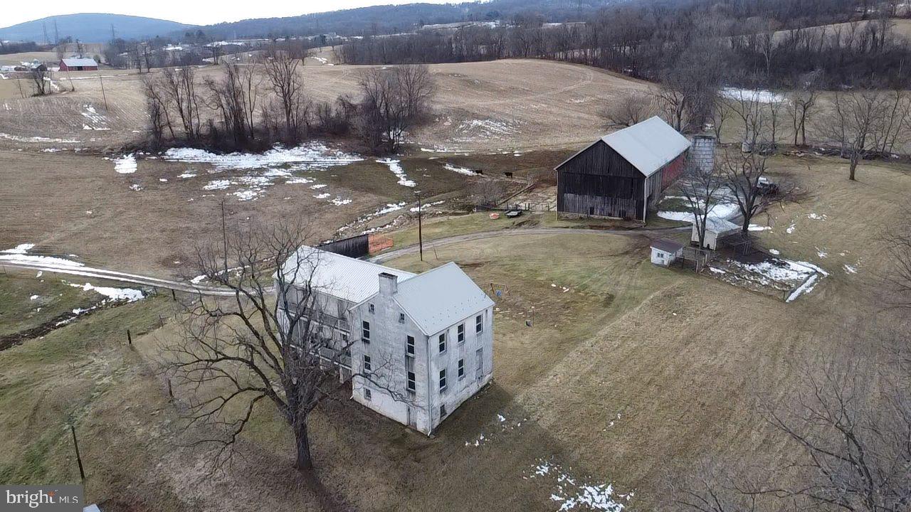 Rare opportunity to purchase a farm in the Middletown Valley. This property is improved with a historic mid 1800's german "L" style residence which features almost 3,000 SF above grade living area, 9' ceilings on both levels, large rooms, four fireplaces, a main ornate staircase and a second functional staircase, a two level 33' long porch/balcony, and some original trim and hardware, . The front section of the home is 'move-in ready' and includes a large kitchen/breakfast room, living room, 2 bedrooms, full bathroom; the back section (two large rooms on each level) and the porch/balcony are ready for finishing touches. Recent updates include new metal roof with snow guards and new gutters (2022), new windows (2023), new Regal Star furnace (2023), new electric panel (2022) and mostly new wiring. The cellar is accessible both from the interior and the exterior.
Farm features include a circa 1851 seven bay 130' x 48' bank barn served with water and electric. The lower level has wooden cattle stalls and a 16' wide x 11' tall 'drive-through' machine shed. The stone foundation, beams and posts are in excellent condition. New metal roof and guttering installed in 2013. Additional agricultural buildings include two chicken coops with fenced runs and water spigots; a run-in shed; and a pig barn
The soils are excellent: 26% of the property is classified as prime farmland and 50% of the property is classified as farmland of statewide importance. The property includes approximately 72 acres of tillable land, 14 acres of fenced pasture and 31 acres of forest. There is a spring fed waterer in the pasture which must remain in place until 2030. In 2024, fifty acres were planted in row crops and 21 acres were used to grow hay. The topography ranges from gently rolling to rolling; slopes are primarily between 5% and 15%.
Water features include two 'year round' streams two intermittent streams and several springs. Grindstone Run (width ranges from 12' to 20') traverses the property for 1,500 linear feet; a small but flowing tributary of Grindstone Run also crosses the property for 1,500 LF.
No subdivision rights remain (MALPF easement) but tenant houses are possible. The property is subject to a 150' wide easement with Potomac Edison for above ground electric lines and a 60' wide easement with Dominion Energy for a buried natural gas line and a sewer line easement with the town of Myersville.
Note: The SDAT record lists the wrong acreage. The Property is 130.055 acres per boundary survey performed in 2020.