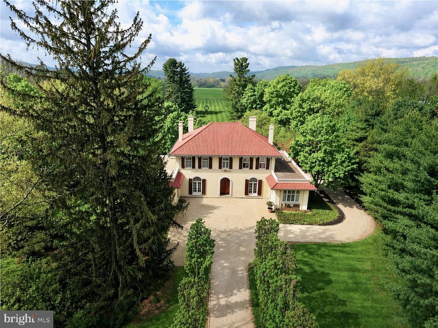 Set on 4.7 manicured acres just minutes from Saucon Valley Country Club, Lanark Manor is a rare 1920s Italianate estate restored by internationally recognized designer Jeffrey Bilhuber and featured in national publications for its refined aesthetic. A private tree-lined approach reveals Mediterranean rooflines and commanding architectural symmetry. Inside, soaring ceilings and arched French doors with fanlight transoms frame sweeping green vistas, creating a seamless dialogue between architecture and landscape. Mornings begin with quiet laps in the pool as sunlight stretches across the rolling lawns. Evenings unfold beneath the columned loggia overlooking beautifully scaled grounds designed for elegant entertaining and relaxed retreat. A heated detached garage and workshop provide space for collector vehicles, craftsmanship or curated pursuits. Whether envisioned as a weekend escape or a full-time residence, the estate offers a sense of arrival rarely experienced. For the buyer who values land, architectural integrity and proximity to premier golf and commuter routes, this is an estate of uncommon scale and quiet distinction. Opportunities of this architectural pedigree and acreage rarely come to market in Upper Saucon Township. Located within the Southern Lehigh School District. *BUY WITH CONFIDENCE—PRE-LISTING HOME INSPECTION AVAILABLE * INTERACTIVE FLOOR PLAN AVAILABLE, TOO* Shown by private appointment only.