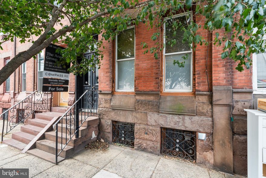 Nestled one block west of Broad Street this stately brownstone has been preserved with remarkable care, keeping its rich history and original character interwoven with slick modern updates. Highlighting original vestibule tiles, original Victorian stained glass transom, 3 sets of glass-paned french doors, rich rustic wood flooring and beautiful original doors throughout. Designed with an architects refined eye the existing color scheme is muted and natural in this well maintained home. You enter the home via broad brownstone steps and classically styled wooden french doors. Into a charming vestibule with antique crazed tiling and beautiful stained glass transom. Light streams through the second pair of frosted glass french doors into the home's foyer illuminating the hall and living spaces. Original flooring throughout gives a warm and rustic feel to this level. You are greeted by an engraved original solid wood stairwell and the living room via the home's traditional layout.  The living room boasts a black carved wood and marble fireplace stealing the show in this sizeable space. Moving through the hall the adjoined dining and kitchen spaces are edged with newer Pella windows. The home has a fully modern kitchen and integrated dining area with tasteful lighting. There is a subtle industrial feel to the space via soft toned steel and glass faced cabinetry, under counter lighting and functional outlet placement for appliances. The dining area can seat 6 and the space also boasts a butcher block seating counter. With a well designed intuitive layout, the kitchen has plenty of counter space and two sinks. Complete with stainless appliances including fridge, microwave and dishwasher. The back of the kitchen is delineated with architectural detail providing a nook for the refrigerator, 2nd sink and huge windows. Use this space as an indoor herb garden or fill with house plants to take full advantage of the sun steaming in. The kitchen's side door takes you to a cozy back patio perfect for a cafe table and chairs. Stow trash along the side patio which includes a hose bib. Moving up the front stairwell you find two nice size bedrooms and modern hall bath. The front bedroom features an original built-in Eastlake-inspired wooden wardrobe encompassing one wall with space for a queen size bed. You enter the back bedroom through the home's third set of original frosted glass french doors. This room has another exquisite carved black fireplace, custom window shades and nook with plaster detail hosting a large bay window. All giving the room an understated refinement and cozy restful vibe with space for a queen size bed. The hall bath has natural green slate floor tiles, a custom feel to the MCM wood vanity and ceramic tile with thin natural stone slab walls and shower surround. The third floor of the home is open and unfinished with new wiring and a fully designed and plumbed full bath offering a wiped clean slate ripe for the creative buyer's vision. Superb location-Steps from local favorites like South Philly Tap Room, Ultimo Coffee, Second District Brewing, & Okie Dokie Donuts.1 block from Passyunk Ave main corridor, 2 blocks from Le Virtue, 3 blocks from Barcelona Wine Bar, 2 blocks from the Philly Food Coop. 3 block walk to either Tasker/Morris or Snyder Ave BSL stops. Make this nuanced Victorian townhome full of character yours today!