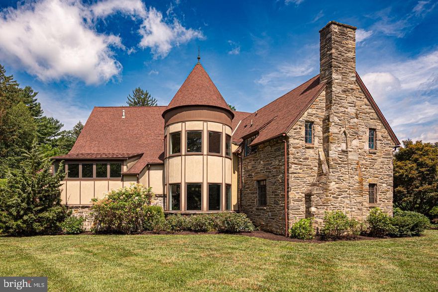 Where Timeless Tudor Charm Meets Contemporary Comfort, Discover the perfect harmony of old-world elegance and modern design in this distinguished English Tudor-style stone residence, thoughtfully expanded by architect Carl Freedman. Set on 1.6 acres of level, beautifully landscaped grounds framed by mature trees, this home offers rare privacy and tranquility in the heart of Wallingford. From the moment you enter, character and warmth abound. The foyer opens to a formal living room with a brick-surround fireplace and a gracious dining room—both with hardwood floors and deep-set windows that fill the rooms with natural light. A central hall leads to a stylish powder room with custom tile flooring and flows into a vaulted great room with recessed lighting and seamless transition into a spacious open kitchen featuring cherry cabinetry, granite countertops, and a cork floor. A highlight of the home is the turret lounge—a striking sunken space with a custom circular tile floor and hand-crafted bar—offering an ideal setting for entertaining and connecting the great room with the living room. Upstairs, you'll find four bedrooms, including a captivating primary suite with turret sitting area and five expansive windows, plus a beautifully appointed en-suite bath. A princess suite with its own bath, two additional bedrooms, and a hall bath complete the second level.The walk-out lower level includes a fifth bedroom with full bath—ideal for guests or an au pair—plus laundry, a rec room, an oversized two-car garage, and a large workshop.
Homes of this character and scale rarely come to market in Wallingford. Enjoy award-winning schools, a friendly community, and unmatched convenience: a 15-minute walk to downtown Media, a 9-minute stroll to Wallingford Station, and quick access to I-476, Center City, and the airport. Come experience the whimsy, space, and architectural beauty your family will cherish for years to come.