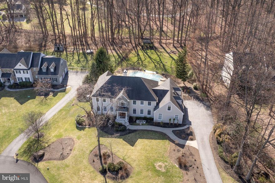 Welcome to 81 Barrington Lane, a truly exceptional estate home offering refined living, extraordinary updates and resort-style amenities in the heart of Chester Springs. Nestled on nearly one acre at the end of a quiet cul-de-sac, this stunning 6-bedroom, 4 full and 1 half bath residence seamlessly blends timeless elegance with modern luxury.
A grand double-door entryway invites you into a two-story foyer, where rich hardwood flooring and raised panel wainscoting set the tone for the thoughtfully curated interiors. The formal living room is bathed in natural light from oversized windows, while the elegant dining room features a coffered ceiling, designer lighting, and a custom pub niche complete with wet bar, beverage refrigerator and icemaker. Perfect for effortless entertaining.
At the heart of the home is a spectacular, fully renovated gourmet kitchen designed to impress. Anchored by an expansive quartz island with seating and a secondary sink, the space is equipped with top-tier appliances including a GE Profile oven with Wi-Fi capability, Monogram induction cooktop with hood vent and pot filler, Sharp convection oven and Fisher & Paykel dishwasher drawers. An oversized farmhouse sink overlooks serene backyard views, while custom cabinetry offers exceptional storage with pull-outs, hidden organization systems, a built-in pantry system and a beverage station complete this space. Sliding glass doors from the kitchen lead to a two-tiered deck with pergola and access to your private backyard retreat with heated saltwater pool with spa and fire pit. Perfect for relaxing or entertaining in a peaceful, picturesque setting.
Back inside, the newly designed drop zone located off the kitchen provides added convenience with direct access to the three-car garage.
The adjoining family room is nothing short of breathtaking, featuring soaring cathedral ceilings, a floor-to-ceiling wood-burning fireplace, custom built-ins and a dramatic wall of windows that frame the picturesque setting. A private study with French doors opens to a tranquil terrace patio, offering the ideal work-from-home retreat. A well-appointed powder room completes the main level.
Upstairs, a catwalk overlooks the family room below and leads to the luxurious primary suite, privately situated in its own wing. This serene retreat features a tray ceiling, custom built-ins, a sitting area with beverage station and two custom walk-in closets. The spa-inspired primary bath has been beautifully renovated with a double vanity, designer tilework, a spacious walk-in shower with decorative niche inlays, a freestanding soaking tub and a private water closet.
The upper level continues with 5 generously sized secondary bedrooms, including a beautifully updated hall bath with double vanity and stylish finishes, as well as a Jack-and-Jill suite with vaulted ceilings and skylight. A newly designed laundry room with automatic lighting and pocket door and a convenient secondary staircase enhances everyday living.
The fully finished, walkout lower level is an entertainer’s dream. This expansive space features multiple gathering areas, a fully equipped kitchenette with built-in appliances, a billiard room accessed through striking stained-glass doors and a custom media/theater room with stadium seating. A sunroom with tiled flooring provides direct access to the outdoor oasis. Also conveniently located on the lower level of the home is a dedicated dressing room for pool guests with lockers and a full bathroom with double vanity.  Additional highlights include a home office nook, exercise area & ample storage. The lower level is also a great space guests, in-laws or au pair. This turnkey residence offers an unparalleled lifestyle with exquisite craftsmanship, thoughtful upgrades and exceptional indoor and outdoor living spaces.  Incredible location! Access to routes 113, 30, 202 and PA Turnpike. Enjoy a peaceful setting with close proximity to nearby shopping, dining and more!