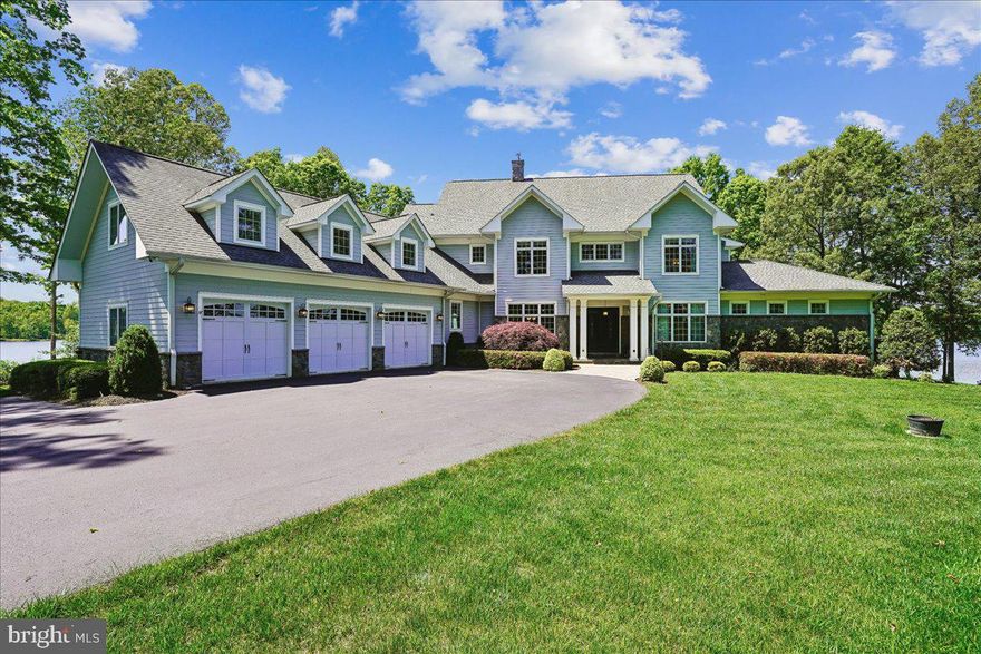 Set along an extraordinary 470 feet of pristine shoreline on the private side of Lake Anna, an hour drive south of the Nation’s capital, this meticulously maintained 6-bedroom, 5.5-bath home offers a rare combination of refined luxury and one of the most breathtaking panoramic views on the lake. With a private 2-slip boathouse and an oversized 3-car garage, this residence is as functional as it is unforgettable. From the moment you enter, the home reveals a seamless blend of craftsmanship and scale. Brazilian hardwood floors guide you through a grand foyer into the soaring great room, where a dramatic 20-foot ceiling and a striking wall of windows frame uninterrupted lake vistas. Electronic blinds provide effortless control, while a fireplace anchors the space with warmth and elegance. At the heart of the home, the sophisticated and inviting chef’s kitchen includes a Wolf 6-burner range, SubZero refrigerator/freezer, granite countertops, and a massive island designed for gathering. A tray ceiling with ambient backlighting and a cozy fireplace elevate the space further. Just beyond, the breakfast room is enveloped in oversized windows, creating the sensation of dining directly above the water. The main-level suite is a private retreat, thoughtfully positioned to capture sweeping lake views. It features a spacious bedroom with tray ceiling, fireplace, and Brazilian hardwood flooring, along with a sunlit sitting room wrapped in windows for a truly panoramic experience. The ensuite bath offers a spa-like escape with a jetted soaking tub, oversized frameless shower, heated tile floors, dual vanities, and an expansive walk-in closet. A secondary main-level bedroom suite provides comfort and privacy for guests, complete with its own ensuite bath. Additional main-level highlights include a formal dining room with tray ceiling, a well-appointed bar/buffet with beverage refrigerator, a large walk-in pantry, mudroom with custom cherry cabinetry, half bathroom and a fully equipped laundry room with granite surfaces and Samsung washer/dryer. The upper-level features two generously sized bedrooms, each easily accommodating king-size beds, Brazilian hardwood flooring and private ensuite bathrooms. A bright and inviting sunroom, also finished with Brazilian hardwood flooring, is surrounded by windows that frame scenic views of the lake, creating a serene retreat. The lower level is designed for entertainment and relaxation. A large family and game room offers ample space for a pool table, ping pong, and additional seating areas. The well-appointed bar includes granite countertops, a bar sink, beverage refrigerator, and dishwasher, making it ideal for hosting. Walk-out access leads to a spacious covered patio, providing a comfortable outdoor area rain or shine. A dedicated media room with soundproof insulation delivers an immersive viewing experience. Two additional bedrooms are located on the lower level, each large enough for king-size beds and featuring private sitting rooms surrounded by windows with stunning lake views. Bedroom #6 also includes walk-out access to its own private patio. Additional highlights include an oversized 3-car garage, four large storage rooms, and a whole-house generator for added peace of mind. The private boathouse is perfectly positioned to take full advantage of the property’s expansive waterfront, offering two boat slips with lifts, a screened room for relaxing by the water, and additional storage. With unmatched views, extensive waterfront, exceptional indoor and outdoor living spaces, and an expansive composite deck, this property represents a rare opportunity to own one of Lake Anna’s premier private-side estates.