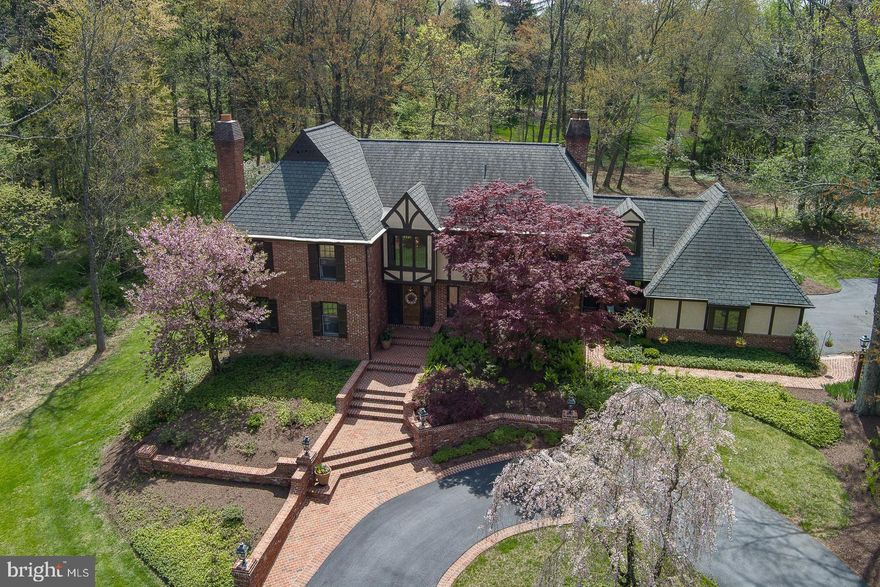 Welcome to 143 Jaffrey Road, an exquisite brick estate set on an expansive 4.4 acres in the prestigious Radnor Hunt enclave of Malvern. Through the grand brick entry gates, this exceptional property is nestled within one of the area’s most sought-after locales in Willistown Township. The home is elegantly framed by a circular driveway and is highlighted by beautifully manicured grounds. Offering 4 spacious Bedrooms, 4 full Baths, and 1 half Bath, this residence is further enhanced by stunning outdoor brick walkways, a charming front porch, and a generously proportioned patio, perfect for entertaining or quiet reflection. Impeccably maintained and thoughtfully designed, this home features two distinct front entries. A leaded glass entry opens to the main Foyer with its soaring two-story ceiling and gracefully turned oak staircase setting the tone for the sophistication found throughout. The Main Floor showcases gleaming pegged hardwood floors, exquisite solid doors, plaster walls and custom millwork that add warmth and elegance to every room. The sun-drenched, two-story Great Room/Family Room is a showpiece, with its breathtaking views through expansive floor-to-ceiling windows and two sliding glass doors that bring the outside beauty into the room. The space is anchored by a stately raised hearth brick fireplace and highlighted by a magnificent beamed ceiling. Adjoining this room is the spacious Kitchen/Breakfast Room, featuring a marble center island with a hammered nickel prep sink and a convenient second dishwasher. Top-tier stainless steel appliances, including a six-burner Viking cooktop, KitchenAid double wall ovens, Bosch dishwasher, and SubZero refrigerator, complete this gourmet kitchen. The Breakfast Room offers access to the outdoor patio, which is framed by elegant brick sitting walls and boasts a tranquil, private backdrop. The formal Living Room features the home’s 2nd fireplace with marble surround and provides a refined space for relaxation, while the expansive Dining Room, accented with crown molding and chair rail, offers the perfect setting for intimate meals or large formal entertaining. A richly appointed Study features custom paneling and built-ins, with an area designated for a wet bar, complete with an inset copper sink. This space is ideal for a Home Office, entertaining or a second Family Room. A separate Family Entry Area off the Kitchen includes a Mudroom, Laundry Room with convenient garage access, and a full Bath with a stall shower, making it easy to transition between the home and outdoors. The 2nd Floor features an impressive overlook to the main level and a large triple window that frames serene views of the front yard. The luxurious Primary Suite is a private retreat, with two walk-in closets and access to attic storage plus a cozy Sitting Area. The ensuite Primary Bath offers dual vanity areas, a deep soaking tub, and a corner stall shower. Three additional Bedrooms are all generously sized, each with hardwood floors beneath the carpet, ample closet space, and one with a cedar closet and ensuite Bath featuring a tiled shower and clear glass doors. The second-level Hall Bath features a tiled tub/shower combination. The Lower Level presents an exciting opportunity for future expansion, with one room currently finished, offering endless possibilities for customization. Perfectly situated within the award-winning Great Valley School District and also close to the area’s finest private academies, the property is mere minutes from the shopping and restaurants of Malvern Borough, West Chester, and downtown Wayne, offering unmatched convenience to train stations and easy access to Philadelphia, Wilmington, and NYC. Don't miss this opportunity to experience the seamless blend of tranquility and luxury that defines 143 Jaffrey Road.