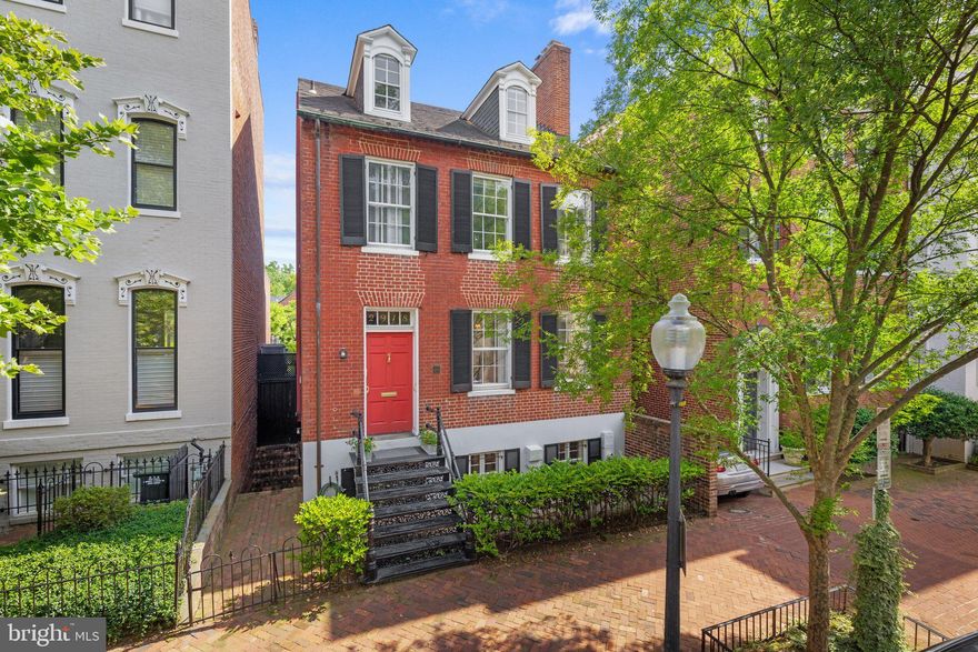 Built in 1823, this authentic Federal home is one of three distinguished houses shown on the south side of West Street, between Washington and Greene Streets, on James Keily’s map of Georgetown from 1851. This rare residence has been meticulously preserved and modernized by the present owner, offering an exquisite blend of historic charm and contemporary convenience. The property is further enhanced by an impressively deep south garden, a staple of the Georgetown Garden Tour since its inception, known for its extraordinary plantings, low horizon line, and general orientation that create a captivating landscape enjoyed from every level of the house.

Upon entering, the generous entry hall showcases original details and 10-foot ceilings, setting the tone for the elegance found throughout the main level. The double drawing room, filled with natural light from two exposures, features original fireplaces, antique light fixtures, and built-in bookshelves, creating a timeless and classic Georgetown space. At the end of the hallway, a butler's pantry includes a south-facing window, coat closets, a wet bar with a fridge, a powder room, an elevator, and access to a charming south-facing porch, providing both practicality and style.

The ground floor is designed for both elegance and functionality. A side entrance leads to a hallway flanked by storage and access to a second powder room. The large, light-filled kitchen boasts granite countertops and backsplash, Leicht cabinetry with modern conveniences such as a fold-out pantry, piston drawers, and roll-out cabinets. Top-of-the-line appliances include a Sub-Zero refrigerator with two freezer drawers, a five-burner cooktop, a built-in microwave, and a wall oven, complemented by an additional bar fridge and Sub-Zero freezer behind the granite bar. Adjacent to the kitchen is a spacious utility room. This level also features a large dining room with a fireplace and a cozy, light-filled family room with built-in cabinets, offering direct views and access to the garden through large glass doors.

The second floor comprises two expansive, light-filled bedrooms, each with matching fireplaces and en suite bathrooms. One of the bedrooms includes a dressing room with a large window that provides abundant natural light. Double doors connect the rooms, offering flexibility in how the space is enjoyed. The back bedroom has elevator access, adding to the home's modern conveniences.

The third floor has two additional bedrooms and a split bathroom with a water closet, providing ample space and privacy. This is a rare opportunity to own a fine example of Federal architecture. The significant historical value and modern amenities is perfect for those who appreciate the timeless elegance and functionality of Georgetown's architectural heritage.