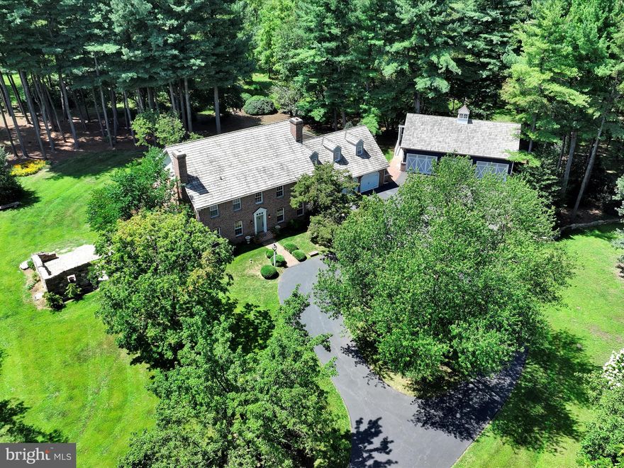 Classic design meets contemporary craftsmanship. This formidable estate represents the soul of American Colonial architecture, combined with the strength and precision of modern construction. The 5,091 sqft solid brick home rests in the middle of a 5-acre wooded lot. The grounds have been carefully curated, and are woven with newly laid stone walls, along with a custom brick patio encircled by hand-built stone ruins that will soon be overtaken by freshly planted wisteria (flowering vines). The home itself was built in 1979 with an extremely custom design. Notable features include random-width plank pine floors fastened with traditional cut nails, custom built-in cabinetry and shelving throughout, a multi-tiered sunroom lined with Pella windows, dual brick fireplaces, a wood stove, and a screened-in brick patio. The fully finished basement includes a tavern-style wet bar.  Oversized closets and ample storage space throughout. All bathrooms have been tastefully renovated with tiled showers and radiant floor heating. The Sellers have spared no expense during their tenure, adding over $600,000 of major upgrades; including a completely remodeled full chef's kitchen with a commercial grade dual-fuel 8-burner 25,000 BTU Blue Star oven/range with true wok capability, a Wolf hood with riser shelves and heat lamps, a 48-inch SubZero refrigerator, and dual farmhouse sinks—each with a Miele dishwasher. The Sellers also constructed a 1,424 sqft detached garage, which is designed to be a truly professional mechanic's shop. The garage has extra-thick concrete floors and three (3) oversized 12x8 bay doors, one of which opens vertically into a vaulted ceiling to enable the installation of a professional grade two-post rotary car lift. The garage exterior has a covered wrap-around deck, cedar shake roofing, 6-inch copper gutters and spouts, and a cupola with a copper weathervane. The interior is lined with knotty pine wood walls. It contains an array of special upgrades, including a compressor, high voltage electric for EV or commercial use, and numerous Husky brand work tables and tool cabinets; all of which remain with the property. The second floor of the garage is an additional finished space that could be used as an office or lounge. Both the kitchen and the garage were constructed in 2023. Other recent upgrades include the installation of a Generac Generator (2023), a new high-SEER electric heat pump HVAC system (2023), and a high efficiency wall-mounted propane boiler for backup heat [kicks on when weather drops below 48 degrees] (2023). This property is in Cornwall-Lebanon School District (South Lebanon Elementary School), and is directly across the street from South Hills Park, which offers a large collection of playgrounds, ball fields, tennis courts, pavilions, walking/biking trails, disc golf, and a great hill for sledding. Also right around the corner from a Lebanon Valley Rail Trail access point, which provides many miles of pathway for biking, running, horseback riding, and cross country skiing. Very close proximity to local schools and hospitals (less than 1/2 mile from the VA Hospital, and 1.5 miles from WellSpan Good Sam). This is an incredibly unique opportunity. Seize your moment!