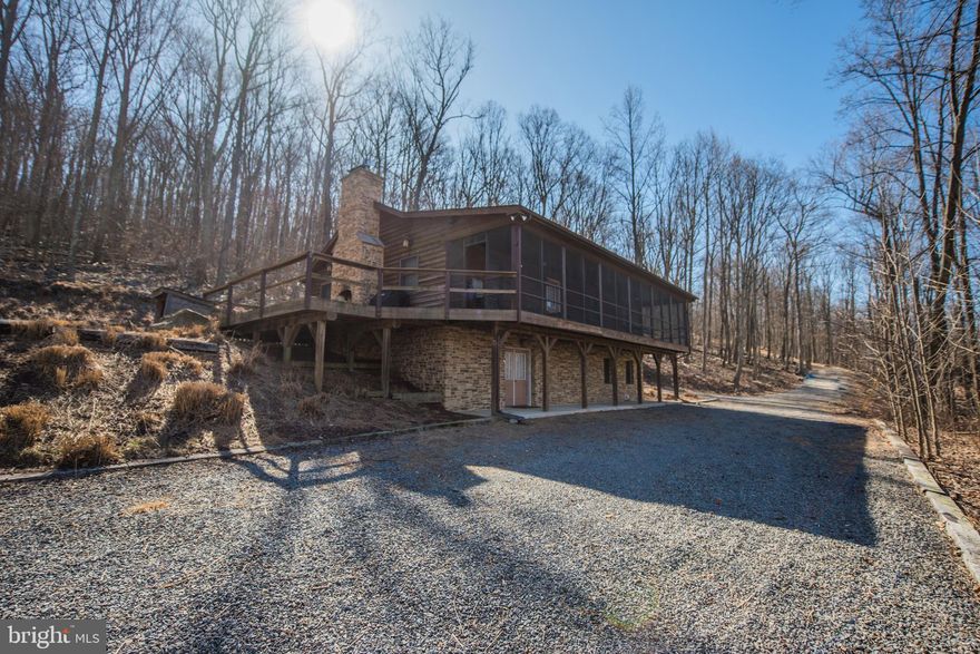 Retreat to the woods where comfort and relaxation await you. Stone WB Fireplace in the great room adds a cozy touch to this spacious room combining kitchen, dining and living areas with vaulted ceilings. The kitchen features a stand-alone island, great for preparing meals, gas range, dishwasher, built-in microwave and Corian counter top. Completing the main level are 3 Bedrooms and 2 baths. Wood floors and solid wood doors throughout for added value. Finished basement features 2 rooms that are currently being used as  4th and 5th bedrooms.  They would be perfect for a den, office or exercise room since they do not have windows for egress, or continue to use them as additional sleeping space.   Spacious Family room with gas fireplace is prefect for overflow for guest and/or entertaining. An inviting screened porch wrap arounds to an open deck with outdoor Fireplace, providing a pleasant setting for quiet cookouts, entertaining friends or simply savoring the out-of-doors. Driveway to main level as well as the lower level ensures you can avoid having to climb steps to access the home. This home is situated on a 3.87 wooded acre lot in a Cacapon River access community where one may enjoy fishing or lazy river float, and/or a picnic. Enjoy a breath of relief from this fast-paced world and let this be your personal hideaway retreat.