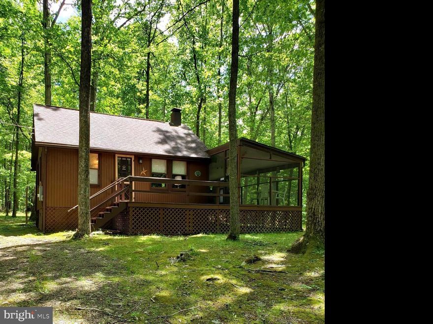Adorable  cabin located in the woods west of Berkeley Springs.  the cabin features include a large screened porch, could be used for sleeping, an open front porch and a sleeping loft.  Sit by the large fire pit and enjoy the sounds of nature.  Community has a private access lot on the clean, clear Cacapon river and also public access areas.  Come canoe, kayak, tube and fish on the 3rd cleanest river on the east coast.  Comes mostly furnished with kitchen items also.  Lot is wooded and level, great for your retreat times.Te inside is open and very cozy with a woodstove to knock the chill off on cool days and evenings.