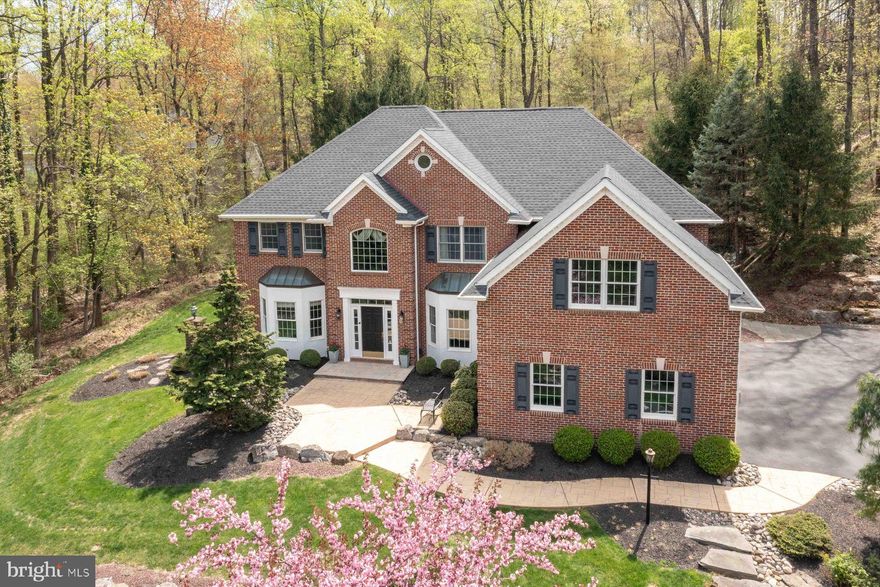 Welcome to this impressive all-brick estate in Center Valley, where timeless elegance meets modern luxury. Set on a private 1.5-acre lot within an established neighborhood, this beautifully crafted home offers privacy and convenience in equal measure.
A grand two-story entryway greets you with abundant natural light and sets the tone for the open, inviting floor plan. The first floor features a flexible office or guest bedroom with full bath access, perfect for today's evolving needs. The heart of the home is the open-concept kitchen and family room, where coffered ceilings, detailed custom mouldings, and expansive windows create a warm and welcoming space. The gourmet kitchen is a chef’s dream, featuring a Sub-Zero refrigerator/freezer, Miele wall oven, and wine refrigerator; a spacious design that flows naturally into the family room anchored by a cozy gas fireplace. Formal living and dining rooms provide elegant spaces for entertaining. Upstairs, the spacious primary suite offers a true retreat with a separate sitting room, two walk-in closets, and a luxurious spa-like bathroom featuring a soaking tub and high-end Toto toilets found throughout the home. Each of the three additional bedrooms includes its own en-suite bathroom, ensuring privacy and comfort for family and guests alike. Additional conveniences include a thoughtfully designed mudroom with custom-built-ins and a desk area, along with both front and back staircases for easy access throughout the home. The fully finished basement expands the living space with a large recreation area, a stylish wet bar with a wine refrigerator and dishwasher, and a full bathroom — ideal for hosting gatherings or creating a private retreat. The home is equipped with modern systems for peace of mind, including a roof replaced in 2020, new heating and AC systems installed in 2022, a whole-house generator, and upgraded 400-amp electrical service. Outside, the professionally landscaped grounds are designed for relaxation and entertainment, featuring mature trees, beautiful hardscaping, and a stunning bluestone patio complete with a built-in fireplace and grill. A spacious three-car garage rounds out this exceptional property, offering ample storage and parking. All of this is located just minutes from shopping, top-rated schools, major highways, and everyday amenities.