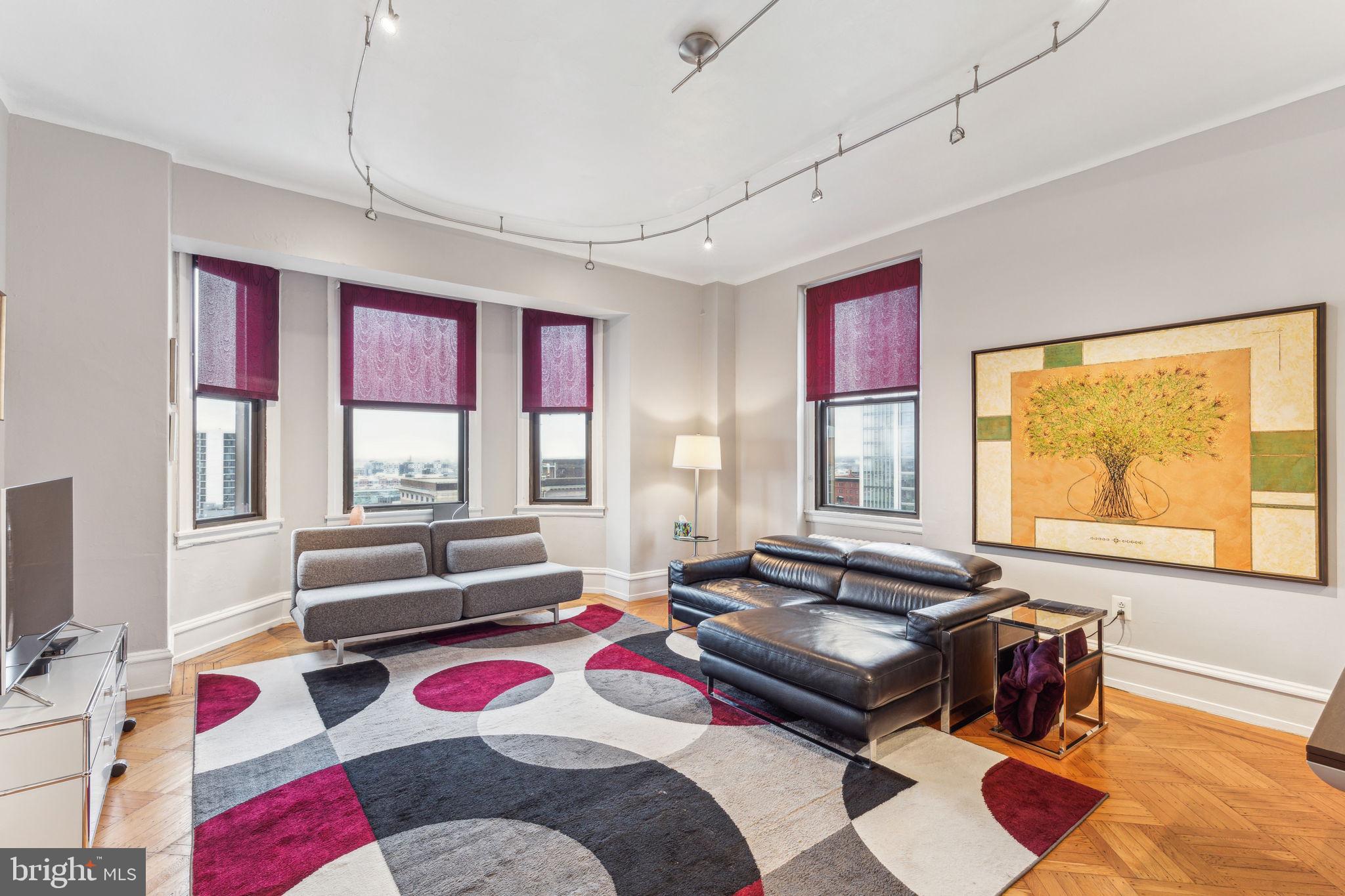 This beautifully renovated corner unit on the 12th floor at the Lenox Condominium offers an exceptional living experience. One of the few units with split system central A/C—an impressive and rare upgrade—this home combines modern comfort with classic charm. The spacious, open-concept kitchen has been fully renovated and features sleek custom cabinetry, stainless steel appliances, and elegant quartz countertops, making it a true highlight of the home. Parking is a breeze with a deeded, gated on-site parking space available and included with the sale behind the building (space G1 - please note to include separate tax ID when submitting your offer).
Large double-pane windows throughout allow natural light to pour into the rooms while offering stunning views of the city. The living room boasts tall ceilings (at least 10') and expansive southern and western views, creating an airy and bright atmosphere. It is further enhanced by an original decorative mantle and a bay window. The generously sized bedroom features a walk-in closet, ceiling fan, and both northern and western exposures. A modernized bathroom and plenty of closet space complete this beautiful home.
The Lenox Condominium is a landmark building designed by renowned New York architects Clinton and Russell, originally built in 1920 and converted into condominiums in 2004-2005. It boasts high ceilings, large rooms, and an abundance of natural light, maintaining many of its original architectural elements. The building offers 24/7 doorman service and is ideally located at the southern end of Mid-town Village in Washington Square West. You’ll be just two blocks from the vibrant shops, restaurants, theaters, and nightlife of Midtown Village, Walnut Street, and the Avenue of the Arts, as well as a short walk from Thomas Jefferson and Pennsylvania Hospitals.
The condo fees cover heat, hot water, high-speed internet, and door staff. Residents are responsible for their own electricity and cable TV. There’s also the potential for additional storage available for a small fee, and the building is pet-friendly. For those seeking fitness options, gyms are located within a few blocks. Public transportation options are plentiful.