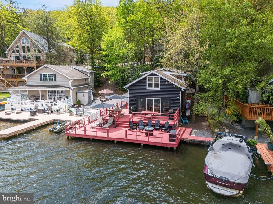 Experience lakefront living at its finest in this fully renovated and designer-furnished retreat. 36 South Lake Drive is a 5-bedroom, 2-bath getaway that blends rustic charm with modern comforts—all just steps from your private dock and panoramic waterfront views. Inside, the spacious layout comfortably sleeps 16 and features a 23x13 living room with sliding doors that open to a lakeside deck. The updated kitchen includes a Samsung fridge, electric stove, microwave, and dishwasher. A cozy bedroom with deck access for the early risers, and full bath complete the first floor. Upstairs, four additional bedrooms and a full bath with generous dimensions make hosting a breeze. Modern conveniences include central AC, a water softener, recessed lighting, high-end washer/dryer combo, and a remote-controlled HVAC system for year-round comfort. Outside, gather around the private fire pit, store your gear in two sheds (16x12 and 6x8), or relax under umbrella-covered seating with the lake just steps away. This idyllic family retreat or lucrative rental property includes private off-street parking for 8 vehicles. Immediately next door is 34 S Lake Drive, which is also for sale. The seller of these incredible properties may consider improved terms for buyers interested in purchasing both properties. The sale includes all fixtures, furnishings, and appliances.