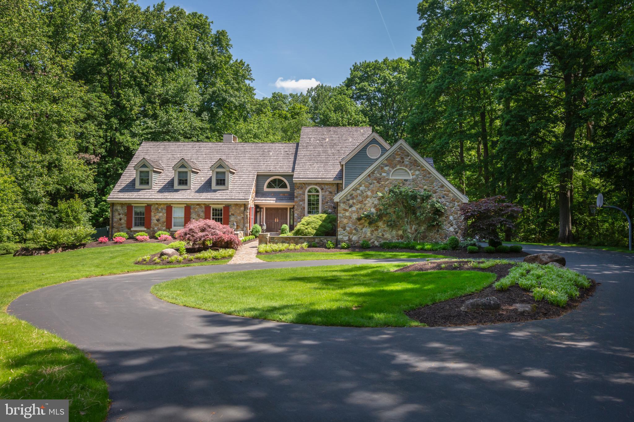 Serenity is the watchword for this private, sun-graced, well-located haven. Carefully designed, with impeccable care and thoughtful improvements, this custom-built, 4-bedroom home has a coveted main floor bedroom, four wood-burning fireplaces, and a wooded backdrop with pool. With high ceilings, substantial millwork, and quality doors and hardware, the classic beauty of this home is evident. A lovely walkway, flanked by mature plantings and stone wall, leads to the front door and its soaring, two-story entrance. The fireside living room, with vaulted ceiling and large windows for abundant sunshine, also has built-in bookshelves and a fireplace. The formal dining room has two sets of French doors leading to the exterior deck overlooking the inground pool and lush, private lot. The recently renovated kitchen makes cooking a delight for the chef. No detail has been spared: Plain & Fancy custom-white cabinetry with an inset door is complemented by quartz, granite, and wood countertops, center island with seating, eye-catching backsplash, a deep sink, and wine fridge. All appliances are top-quality, and include a Kitchen Aid double wall oven and GE Monogram refrigerator. The breakfast area, with multiple windows, is sunny and cheerful. The kitchen opens to the family room, with its cathedral ceiling and compelling, floor-to-ceiling stone fireplace. The many windows look out onto the wooded exterior, with French doors leading to the deck. The first-floor, carpeted bedroom is comfortable, with French doors to the exterior terrace, as well as a fireplace, large window, two closets, and luxurious en-suite bath with large, dual vanity, soaking tub, and separate, glass-door shower. A handsome home office with a built-in desk and storage faces the front of the home. The first level also has a renovated powder room; the laundry room leads to the driveway and attached three-car garage. A graceful staircase flanked by a Palladium window leads to the second level and its three bedrooms. One bedroom has an updated, en-suite bath and two closets. The other two bedrooms are joined by a new bath that has a dual vanity, soaking tub, and stall shower. The finished, walk-out lower level is ideal for entertaining. With a main room with fireplace and fully equipped bar, as well as a pool/game room and personal gym, there is also a full bath on this level and additional storage. Outside, the deck overlooks the rear, wooded backdrop and beautiful, inground pool surrounded by travertine stone. The deck is enchanting with its peaceful allure: enjoy your morning coffee, summer suppers, or birdwatching from this lovely vantage point. The community of Radnor Hunt and town of Malvern offer so much, including Buttery Bakery, Alba, Kimberton Whole Foods and more. Both Paoli and Malvern train stations have easy access to Center City, with Wilmington, Washington, D.C. and New York City within reach. Your soothing, serene retreat awaits!
