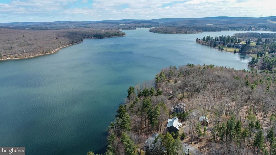 Tucked away at the end of a country road, this fully reimagined lakefront lodge blends fairytale charm with warm modern style, offering over 3,000 square feet of carefully crafted space on a private .58-acre lot with 100’ of deep water frontage on the main body of Deep Creek Lake. Every inch is designed for relaxation, ease, and family—from the gourmet kitchen with custom hardwood cabinetry, live edge finishes, and stainless appliances, to the sprawling primary suite with a tiled walk-in shower and generous closet space. A full-light walkout lower level opens to lake and mountain views, adjoining a spacious rec room complete with log bunks and full bath, and easy access to the lake and outdoor shower. The massive native stone fireplace and vaulted ceilings anchor the main level with warmth and character, while the wire-railed deck stretches toward the water, partially covered for shade and summer dining. A new standing seam metal roof tops it all off, with a detached two-car garage with plenty of storage for all the toys. This place is turn-key, timeless, and built for big family memories.