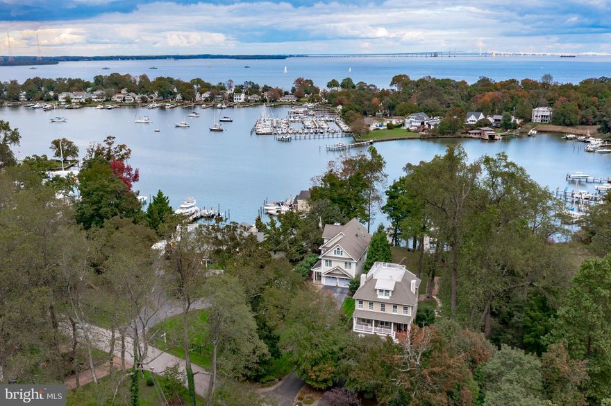 **New Price!!** Fantastic transitional Waterfront home in Bay Ridge  with private, deep  water pier  (5' -6' mlw) on Lake Ogleton. Elevated home with lovely path to pier and beach. Pier offers 10,000 lb boat lift, with two additional slips and room for more. Pier offers water and electricity.  Beach is approximately 40' wide.  Bay Ridge Open Space next door contributes to privacy and access to nature.  There are so many opportunities for play on the ball field across from this home.  This four-level home offers multiple spaces for living, entertaining, working and recreating - from the finished lower level walk-out all the way to the "widow's walk" roof-top deck overlooking the Chesapeake Bay. The two-car garage and expanded driveway offer ample parking space.  The inviting IPE steps and  front porch lead you to the Open floor plan with Brazilian hardwood floors, and a wall of windows opening to nature and water views. Large gourmet kitchen w/ granite countertops and updated cabinets. Elevated dining area and recently added home office. Fantastic primary suite has new carpet, a gas fireplace and killer views of nature and Lake Ogleton! The four upper level bedrooms are en-suite. Three propane-powered fireplaces in lower level, family great-room and primary suite! Bedroom-level laundry room. Outdoor entertaining includes: Fire pit, slate patio, and two Rooftop decks! Finished walk-out basement with garage access, bedroom and full bath,  storage and new carpet. Whole-house generator. Bay Ridge is a highly sought after community with: a community pool, beaches, a marina, club house, playground and sports courts. Annual parades and events are a common occurrence. On-site security is a bonus!  Residents enjoying the one-of-kind  Chesapeake Bay views and boating on Lake Ogleton are a common sight. Fast access to all major commuting routes to DC, Baltimore and the Eastern Shore! ** Bay Ridge is a Special Tax Assessment District and the Community membership dues of $300 year are requested. Additional fees are required for pool and marina memberships.
