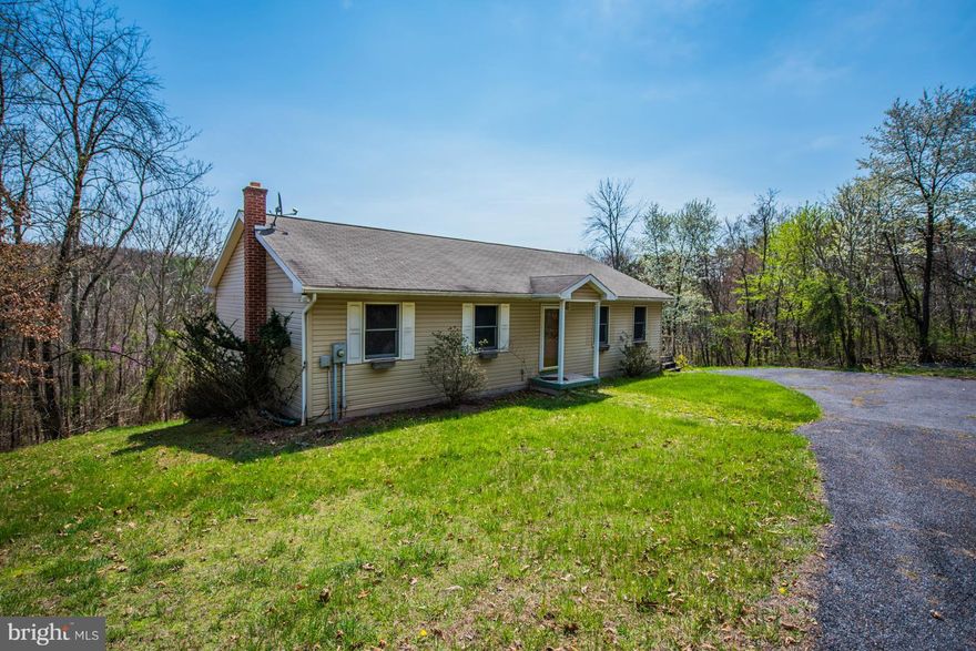 Home is tucked back on the lot for privacy. 3BR, 2BA rancher w/ spacious Living & Dining/Kitchen combo w/ laundry @ Kitchen. Full unfinished walkout basement w/ flue for wood stove for potential living space. Paved driveway + underground utilities.  Comcast or DSL through Frontier is available. Located just 3 miles east of Berkeley Springs in a well maintained community.