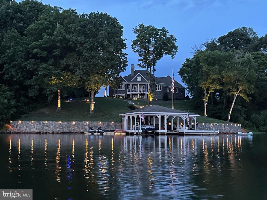 Wake up to sparkling lake views, spend your days on the water, and end each evening with breathtaking sunsets that paint the sky—this extraordinary custom-built waterfront home captures the very best of life on Lake Anna. Designed with a perfect balance of luxury, comfort, and timeless craftsmanship, this remarkable 5-bedroom, 4.5-bath residence offers over 200 feet of pristine deep-water frontage, with approximately 15 feet of depth at the end of the dock, and sweeping unobstructed lake views from nearly every room.  The thoughtfully designed open-concept main level creates an effortless flow between the gourmet kitchen, dining area, and the stunning Great Room, making it ideal for both everyday living and entertaining. The chef’s kitchen features high-end appliances, generous counter space, and custom cabinetry, seamlessly connecting to the dining area—perfect for intimate meals or lively gatherings with family and friends. Anchoring the space is the Great Room, where soaring ceilings, a dramatic stone fireplace, and a wall of windows frame spectacular lake views while filling the home with natural light. 
The main-level primary suite offers a peaceful private retreat, complete with tray ceilings, expansive windows overlooking the water, and a spa-inspired ensuite bath designed for relaxation. Four additional bedrooms and beautifully appointed bathrooms provide ample space and comfort for family and guests.  
Exceptional craftsmanship continues outdoors, where elegant stone columns welcome you at the driveway entrance and natural materials enhance the landscape with flagstone porches, walkways, and patios. The 200-foot natural stone bulkhead and seawall provide both beauty and shoreline protection, while multiple outdoor living areas invite you to fully embrace the lake lifestyle. Enjoy cooking and entertaining at the built-in grill island, gathering around the stone fireplace on the rear patio, or relaxing by the separate firepit area under the stars.  The oversized dock is truly a boater’s paradise, featuring two covered boat slips with lifts, a spacious sun deck, Gorilla Deck composite decking, storage with electricity and running water, hard-wired internet, and a Sonos sound system with eight speakers. Four floating jet ski docks make it easy to enjoy every water activity Lake Anna has to offer.  Additional highlights include a paved driveway, oversized 28x28 garage, whole-house audio system, central vacuum, and most furnishings conveying with the sale—making this home as convenient as it is beautiful.  Whether you are searching for a full-time waterfront residence or a luxurious lakefront retreat, this exceptional property delivers refined design, premium amenities, and unforgettable views. From peaceful mornings on the dock to sunset gatherings by the firepit, every day here feels like a vacation.