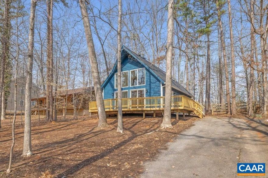 An absolutely darling chalet style lake retreat featuring a dramatic two-story wall of windows and soaring vaulted ceilings spanning the living, dining, and kitchen areas. Cozy up beside the stunning floor-to-ceiling wood-burning fireplace or enjoy nature from the oversized brand-new wraparound deck surrounded by trees. The home offers spacious bedrooms, updated bathrooms, and a charming second-story nook with a balcony overlook. A fenced backyard is perfect for furry friends. The beautifully updated kitchen features brand-new cabinets, granite countertops, and stainless steel appliances. Other major updates include a new roof, skylights, oversized gutters with guards, brand new LVP flooring, new slider, and fresh paint inside and out. Conveniently located just moments from the main beach amenities; playground, tennis and basketball courts, pool, and clubhouse. Whether you're looking for a full-time residence or the perfect lake getaway just outside the historic City of Charlottesville and Monticello, this home offers comfort, style, and modern convenience. Come see what makes this special lake home so easy to love! Agent/owner.,Granite Counter,White Cabinets,Fireplace in Great Room