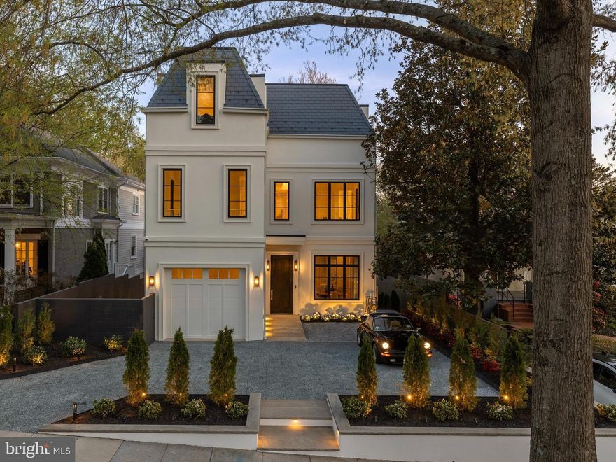 A modern Parisian-inspired stately residence defined by classical proportions and refined contemporary detailing, The Highgate is a newly constructed, custom-crafted home in one of Washington, DC’s most prestigious and tightly held neighborhoods. Ideally sited on a quiet, tree-lined street in Kent, this seven-bedroom, seven-and-one-half-bath residence is fully finished and designed and developed by Silverstone Group. This true ground-up build offers approximately 7,182 square feet across four expansive levels.

The exterior is timeless and restrained, finished in white stucco with custom fabricated gutters and downspouts and a premium EcoStar synthetic slate roof. Marvin Ultimate and Elevate windows flood the interiors with natural light and frame treetop views. Ceiling heights define the architecture throughout: approximately nine feet on the lower level, eleven feet on the main level, ten feet on the second level, and dramatic twelve-foot ceilings on the top level. The great room rises to nearly fifteen feet, creating volume and quiet grandeur.

The main level balances formal entertaining and everyday living, with formal living and dining rooms, a gracious entry foyer, and powder room with custom Calacatta Rosso stonework. A stunning great room with a gas fireplace flows into a chef’s kitchen with paneled Sub-Zero and Wolf appliances, SapienStone Arabescato 4D countertops and full-height backsplash, fully custom cabinetry with Rejuvenation hardware, and an oversized butler’s pantry. Glass doors open to a covered rear deck, roughed-in for a future outdoor kitchen, with stairs to a fully leveled and professionally landscaped backyard.

The second level features four ensuite bedrooms, including a luxurious primary suite with a gas fireplace and two walk-in closets. The spa-caliber primary bath includes heated marble floors, dual showerheads, soaking tub, double vanity, dedicated makeup, and Kohler smart toilet. A second laundry room is also located on this level.

The top level offers a dramatic media room with twelve-foot ceilings and wet bar, two additional ensuite bedrooms, and direct access to a large rooftop terrace with TimberTech decking, outdoor kitchen, and unobstructed treetop views extending into Virginia.

The lower level offers exceptional versatility with a media lounge and wet bar, gym, storage room, mudroom, full-size laundry room, and additional bedroom, ideal for guests, recreation, or extended stays.

Interior finishes include a nine-foot African mahogany front entry door,  7.5" French white oak sand-in-place flooring, extensive custom millwork, bespoke cabinetry, custom doors with Baldwin hardware, and marble bathrooms throughout. Waterworks fixtures are featured in the primary bath and powder room, Rohl Italian brass fixtures in the kitchen, and Brizo fixtures elsewhere. Rejuvenation lighting and three fireplaces anchor the great room, formal living room, and primary suite.

The home is engineered for performance with two Carrier HVAC systems and four independent zones, energy recovery ventilator, and smart thermostats. The residence is fully sprinklered and includes all new water, sewer, electrical, and gas systems. An elevator shaft is provided, with installation available at additional cost.

Technology is comprehensive and future-ready, with Cat6 and coax wiring in every room, in-ceiling Wi-Fi access points, over sixty Klipsch in-ceiling speakers, smart control tablets, and a seven-camera exterior CCTV system.

A private front motor court accommodates two vehicles, complemented by an oversized one-car garage with an EV charger. The rear yard includes a fully integrated rain and stormwater retention system, irrigation, and landscape lighting.

The Highgate represents a rare offering in Kent: a newly constructed, architecturally disciplined residence where classical proportion, modern systems, and refined craftsmanship converge.