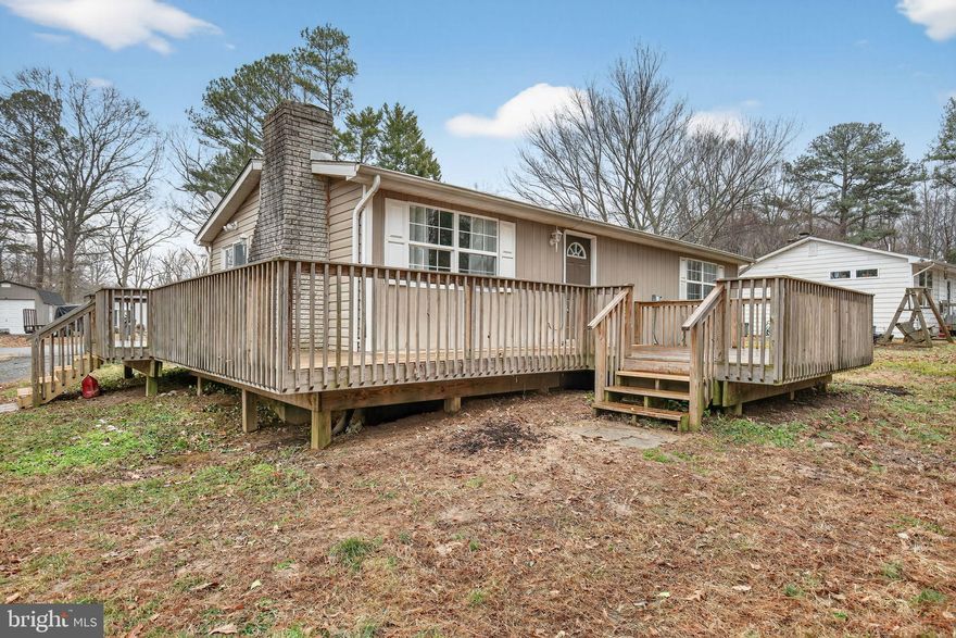 Welcome to the serene Hollywood Shores neighborhood, a lovely waterfront community where quiet living meets coastal potential. This charming 1975 ranch-style rambler is situated on a spacious one-third acre corner lot with no through traffic, offering the perfect blend of privacy and accessibility. The home features two comfortable bedrooms and a shared full bathroom, providing an ideal layout for a primary residence or a peaceful weekend getaway. Upon entering, you are greeted by an inviting living room that serves as the heart of the home, complete with a classic fireplace (chimney capped) that adds a touch of character to the space. The eat-in kitchen features practical vinyl flooring and a sliding glass door that provides easy access to the side deck and convenient views of the driveway.

The exterior of this property is truly its standout feature. A large deck wraps around two sides of the home, offering an expansive area for outdoor entertaining. The dedicated seating area accesses the front door, which is why it faces the water side of the property, which currently backs to lush woods.. Modern essentials are already in place, including an HVAC system replaced in 2014, a well pump updated in 2019, and Breezeline high-speed broadband availability for all your streaming and work-from-home needs. Residents of Hollywood Shores enjoy an incredibly low HOA fee of just $10 per year, with the added option of a separate recreation fee for pool access. With a dual-entrance driveway on Peninsular Drive and Island View, plus a dedicated laundry, this home is as functional as it is full of potential.