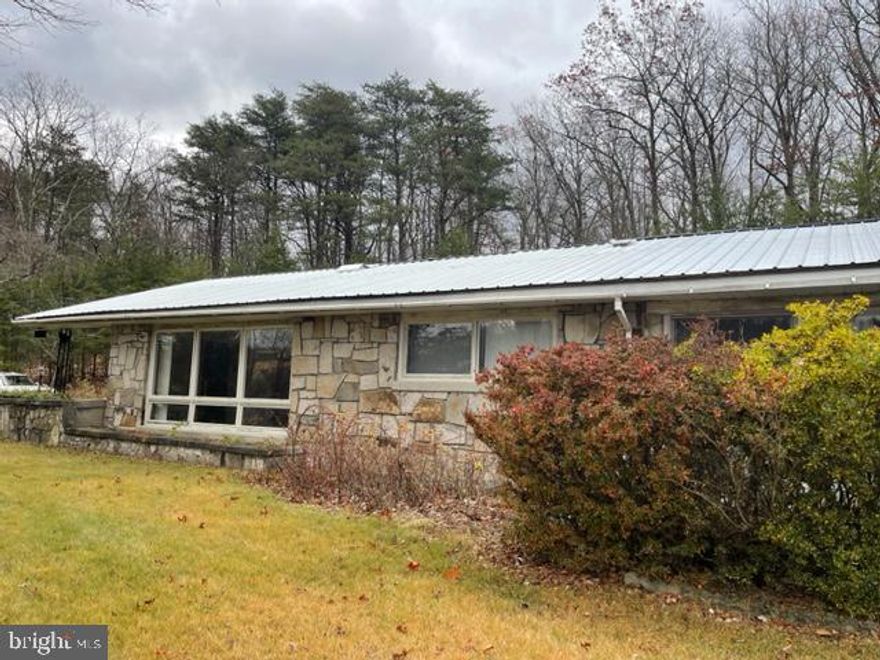 Stone 3 Bedroom Ranch style Home located in Berkeley Springs, WV minutes from downtown.  2.40 acres consists of 5 adjoining parcels. Lots of room to spread out and grow with huge Family room and separate  lower level Recreation Room and Summer kitchen area.  Storage galore includes walk in cedar closet.  City water and city sewer. Attached over sized garage w/mechanics service pit, Shed and more.  For Sale priced at $259,000.