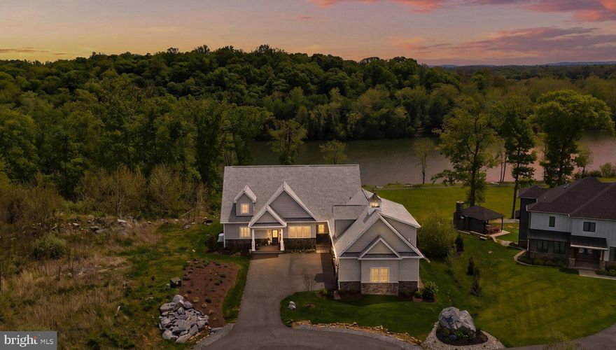 A rare offering on the deep-water Potomac, this custom waterfront residence pairs architectural presence, refined finishes, and a setting designed for life on the water. Located in the gated community of Potomac Overlook Estates, with access to 10 miles of deep-water boating, the property offers a level of privacy, scale, and waterfront experience seldom found in the area. From the covered stone front porch to the private decks, patios, and a private floating dock below, every element was designed to make the most of its riverfront setting. Inside, wide-plank LVP floors, soaring ceilings, and an open main level create an impressive sense of scale. The gourmet kitchen makes a strong impression with an oversized island, quartz countertops, farmhouse sink, and butler’s pantry, all opening to a breathtaking dining area wrapped in windows and oriented to the river. The living room is anchored by a dramatic floor-to-ceiling stacked stone fireplace with custom built-ins. All five bedrooms are true suites, each with its own ensuite bath, including a primary suite designed as a private retreat with a spa bath, soaking tub, dual vanities, and custom walk-in closet. A separate guest suite and loft add flexibility for extended stays without sacrificing comfort or privacy. Outdoor spaces are equally compelling, with a glass-railing deck, expansive tile patio, built-in fire pit, and terraced landscaping leading to the water’s edge and private floating dock. The oversized crawl space and basement area include a full bath, offering exceptional utility after long days on the river. Whether centered around boating, sunset dinners, or weekends filled with guests, this is a waterfront home designed to make the most of deep-water Potomac living.