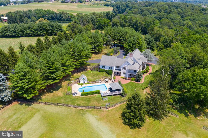 Nestled in Dallastown, Pennsylvania, this breathtaking and majestic property of nearly 50 acres is truly a dream come true. Boasting 6 bedrooms, 3.5 baths, and over 5000 square feet of living space, it is more than just a comfortable home, it's an elegant oasis. Equestrian enthusiasts will be astounded by the horse barn that's home to 6 horse stalls and 10 additional ones that can easily be added on. It includes a 3-year old standing seam roof, a tack room, and washing station. This is truly a must have destination for horse lovers! The rear patio shines with an in-ground saltwater pool, relaxing cabana, pool house with half bath and outdoor shower, and outdoor built-in grill. The property features 15 tillable acres and is subdividable. As you enter the three-story home, you are greeted with elegant marble flooring, high ceilings, large windows, and countless detailing. In the center of the home is a gorgeous dining area set to the backdrop of cherry hardwood beams and flooring, a warm stone fireplace, track lighting, and stunning views. The adjacent gourmet kitchen is bright and inviting, featuring stainless steel built-in appliances, a concrete countertop center island, gas cooktop, breakfast area, large stone fireplace, and access to the covered front porch-- an ideal ambiance for taking in the sights and having a morning coffee. The convenient bar room is the perfect place to make drinks and provides easy access to the pool and patio area. Additional rooms on the main floor include a spacious living room, a dedicated learning area with built-ins and chalkboards, and an elegantly designed powder room with a surrounding hand painted mural and marble tile flooring. Access to the second floor can be found near the bar room as well as the foyer. Located behind elegant French doors with baroque glass detailing, an astounding owner's suite awaits, featuring a sizable sitting room, a wraparound balcony with awe-inspiring views, a warm fireplace, a spacious walk-in closet with built-in shelves for shoes, and a private bath that is highlighted by marble tiles and counters along with a glass encased tile walk-in shower. The owner's suite has its own access to the 2-car garage and back entrance as well. Two additional bedrooms can be found on the second floor, both with plenty of closet space and views of the surrounding property. The third story is home to three more bedrooms and a loft area with built-ins. Adding to an already amazing home is a convenient central vac system, 4-zone heating, stereo system on the 1st floor and patio area, water treatment, reverse osmosis, 2-ft thick fieldstone siding, paddock, room for a helicopter pad or riding circle, and a stylishly designed entrance and driveway that has hosted over 150 guests. Marvel at the scenic wildlife that includes turkeys, deer, birds, and more! Rolling hills and mountain views will take your breath away wherever you stand. Visit this one of a kind property today and see this beauty for yourself!
