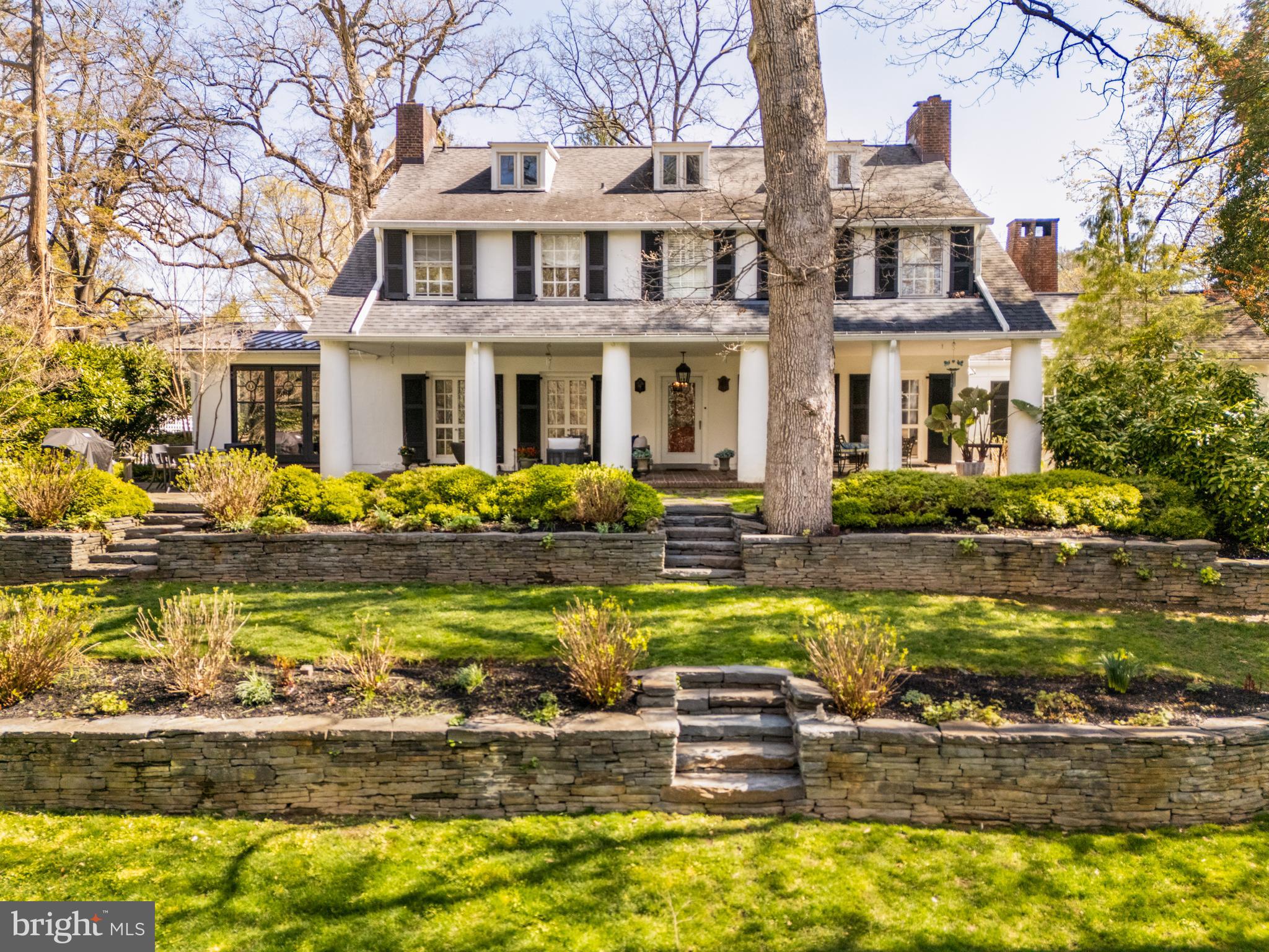 SUNDAY April 13 OPEN HOUSE CANCELLED Nestled on a picturesque parcel once part of the storied Wentworth farm, this exceptional Colonial Revival estate—designed in 1911 by renowned Philadelphia architect Charles Barton Keen—is a rare offering in the heart of Strafford. Keen, celebrated for his work on Reynolda House and the Aronimink and Valley Forge Golf Clubhouses, designed this home and its two neighbors as a cohesive architectural trio.
Set on lushly landscaped grounds, a stone bridge, river rock paths, and a tranquil pond, this home offers a seamless blend of early 20th-century craftsmanship and modern comfort. The front-to-back Center Hall opens to spacious formal Living and Dining Rooms—each with fireplaces and French doors to a stately brick-columned veranda that spans the rear facade.
A sun-bathed Kitchen, fully renovated with custom finishes, opens to a Sunroom addition and charming patio overlooking the gardens. The showstopping barrel-ceilinged Library is appointed with floor-to-ceiling mahogany bookcases and wide-plank black walnut floors. A Solarium with original tile fountain leads to the breezeway and detached Garage.
The second floor offers a serene Primary Suite with fireplace, Sitting Room, and updated Bath, along with two large Bedrooms and Hall Bath. The third floor features two additional Bedrooms and a full Bath—perfect for guests, home office, or studio space. The partially finished lower level includes ample storage, rec space, and newer electrical systems.
Conveniently close to Strafford Train Station, downtown Wayne, Whole Foods, the Strafford Farmers Market, the King of Prussia Mall, Rte. 202, the PA turnpike and 76, this historically significant home delivers timeless elegance, privacy, and convenience—plus a backyard pond. Own a piece of Strafford’s rich history—an heirloom home built to last another century.