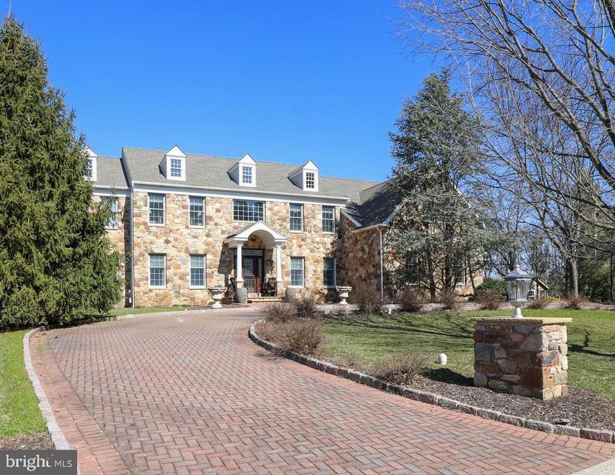 Drive up the remarkable circular EP Henry Paver driveway lined with Belgian Block Curbing leading you up to the natural stone facade. Each of the two driveways are flanked by natural stone pillar lamp posts and surrounded by mature landscaping.  An EP Henry paver embellished walkway invites you to enter the home under a portico and through the newly installed (2022) front door with keyless touchscreen lock. The custom door is complete with etched glass, transom and dual sidelights. A video doorbell informs you of arriving guests. Recently, Hardie Plank fiber cement siding has been installed (2023) on the exterior rear and sides, adding to the beauty and maintenance free aspect of this wonderful home. A new garage overhang (2023) has also been added with recessed LED lighting, adding to the home’s character. A new roof, gutters and all 5 solar powered skylights were installed in 2021. New garage doors and electric openers were installed in 2021. All the exterior work has been done for you! 
The 2-story foyer graced by the grand staircase and dentil molding opens to the rear of the home. The beautiful formal Living Room has Wainscoting, crown molding, hardwood flooring and the first of four natural gas fireplaces in the home. Proceed through the double doors to a spacious Great Room used for entertaining, complete with a natural stone fireplace, ice maker and wet bar with new (2022) wine & beverage system. Wainscoting, crown molding and hardwood floors in the Dining Room create an inviting space for gatherings. A dedicated office with built-in shelving has a peaceful view of the wooded yard. Two new skylights (2021) with remote shades bring plenty of natural light into the 2-story Family Room with a floor to ceiling natural stone fireplace. The chef's kitchen has granite counters, a 6-burner gas stove with stainless hood, Sub Zero freezer and refrigerator, large center island with prep sink, double wall ovens and an abundance of cabinets ready to prepare your culinary creations. Through the kitchen, the inviting Solarium with two new skylights is a great place to relax and unwind with a book. On the second floor find the expansive Primary Bedroom suite with a cozy sitting room featuring another fireplace, two large walk-in closets, a large bonus room (2nd office) and the Primary Bathroom. Four additional bedrooms complete this floor.  Two bedrooms have attached full bathrooms and closets with custom organizational systems. The remaining two bedrooms share a Jack & Jill bathroom. An enormous unfinished, walk-out basement is plumbed for a bathroom and ready for your finishing touches. The large clear span 3-car garage has an electric car charger which was installed in 2021. The second floor AC unit was replaced in 2022. Additional features include a Nest video doorbell and Nest thermostats, DSC security system, foyer chandelier light lift feature, holiday lighting package and interior invisible dog fence in the kitchen and solarium. This home is in the highly rated Central Bucks School District, is close to Doylestown Borough and New Hope with easy access to Philadelphia, New Jersey and New York.