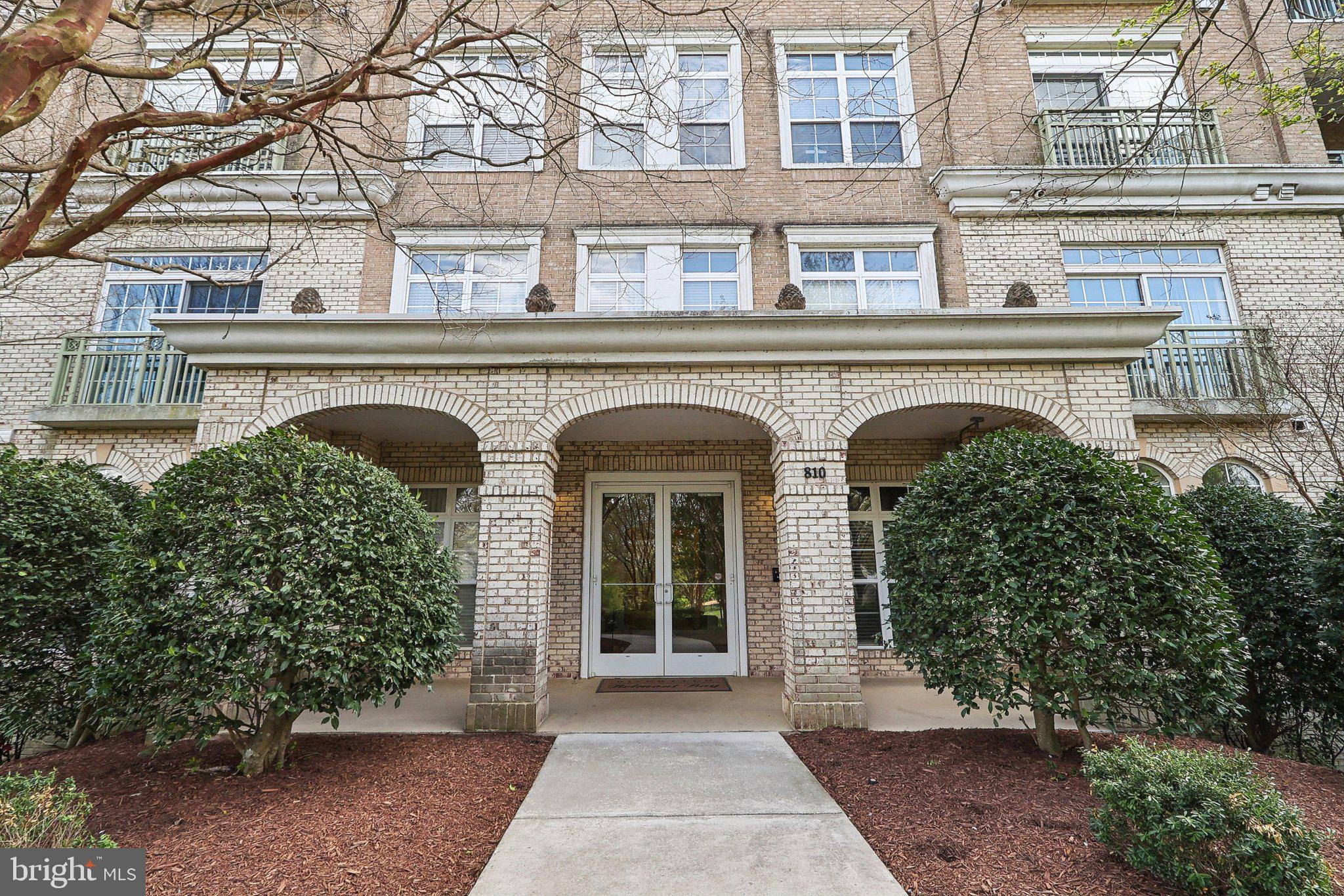 Beautifully designed and impeccably maintained, this 2-bedroom, 2.5-bath ground-level corner condo offers refined comfort and effortless living in the waterfront community of Belmont Bay. Formerly a model unit, the home features a thoughtful and spacious layout enhanced by custom finishes, tall windows, and abundant natural light throughout.
Just off the entry, a custom-built den or office space creates an ideal work-from-home environment, complete with rich built-in bookcases and a functional desk area. The well-equipped kitchen offers extensive cabinet storage, stainless steel appliances, and a large center island with bar seating and a built-in wine rack—perfect for entertaining. A dedicated dining space flows into the expansive living area, where oversized windows frame tranquil views and provide direct access to a private balcony, ideal for morning coffee or evening relaxation.
The split-bedroom layout enhances privacy, with the primary suite on one side featuring a walk-in closet and en-suite bath, and the second bedroom on the other, also with its own walk-in closet and easy access to the second full bath. A powder room and in-unit laundry complete the interior.
In addition to your private outdoor space, residents enjoy access to a rooftop deck with sweeping water views of the Occoquan River and marina—an ideal perch for sunset watching or casual socializing. Belmont Bay offers a true lifestyle community with a full-service marina, walking and biking trails, beautifully maintained green spaces, and frequent neighborhood events. Dining, music, and waterfront ambiance await at nearby favorites like The Harbour Grille and The Spot at Belmont Bay.
Located just minutes from the Woodbridge VRE and Amtrak stations and with quick access to Route 1 and I-95, commuting to D.C., Northern Virginia, Fort Belvoir, or Quantico is exceptionally convenient. Offering the perfect combination of low-maintenance living, scenic beauty, and unbeatable access, 810 Belmont Bay Drive, Unit 102 is an exceptional opportunity in one of Prince William County’s most desirable riverfront communities.