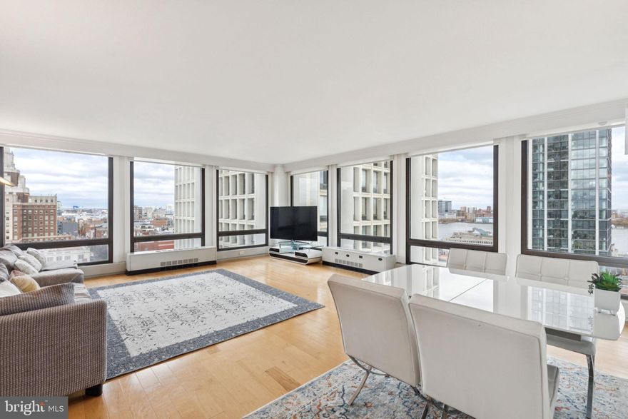 Beautifully updated corner two bedroom with sunrise views over the Delaware River at Society Hill Towers! This spacious two bedroom, one bathroom home features modern updates, walls of floor-to-ceiling windows showcasing spectacular views of the Delaware River and the city, and beautiful hardwood floors throughout. Enter through a foyer with large coat closet into the expansive open great room boasting two walls of windows providing incredible natural light, glass floating shelves, modern wood accent wall, and an open dining area with electric fireplace, perfect for entertaining. Adjacent is the fully updated kitchen with sleek wood cabinetry, light stone countertops, gray tile backsplash, stainless steel appliances, tile floor, and a breakfast bar, ideal for enjoying your morning cup of coffee and watching the sun rise over the river. Next to the kitchen is a laundry closet with stacked washer/dryer. The spacious primary bedroom enjoys great natural light and river views from floor-to-ceiling windows and a walk-in closet. The second bedroom is generously sized and has a deep wall closet. Both bedrooms enjoy use of a contemporary hall bathroom with modern wood vanity, glass enclosed tub shower, and upgraded tilework throughout. Additional home highlights include updated light fixtures, crown and baseboard molding, and excellent closet/storage space throughout. Residents of Society Hill Towers enjoy a 24-hour doorman and all utilities plus basic cable. Access to the building's outdoor seasonal pool, fitness room, storage lockers, and parking in the building's underground garage are available for an additional fee. Also, there is an on-site Philly Car Share, a coin operated laundry room in the basement, and a shopping plaza on site with a market, dry cleaner, beauty salon, and one of Philly's most acclaimed restaurants, Zahav.