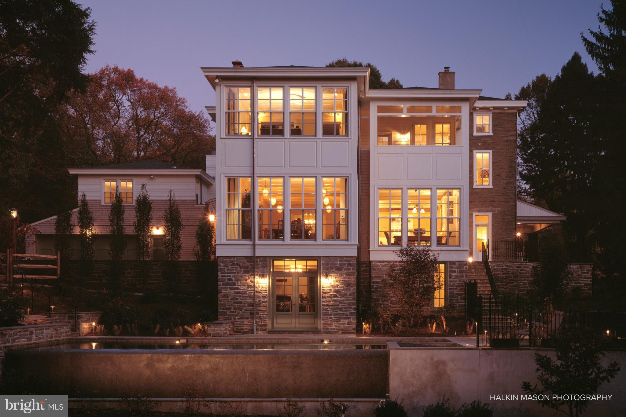 Tucked away in a gorgeous, private and secluded location bordering 300 permanently preserved acres sits this beautifully updated and expanded home. The original section of the home dates to the 1860s, while an eloquent addition and renovation in 2003 by Purdy O'Gwynn Architects seamlessly blended the old with the new, and transformed this house into an incredibly functional and comfortable space. Beautiful original details and millwork, such as deep windowsills, wide width hardwood floors, beamed ceilings, crown moldings and pocket doors are blended with modern design elements and amenities. The front entrance and center hall lead to the large great room with beamed ceiling, huge fireplace and multiple dining areas overlooking the lush grounds. The chef s kitchen with new appliances, real quartz countertops and large center island is open to the great room, creating perfect spaces for everyday living or entertaining. French doors open to the rear brick terrace and grounds. To the rear of the home is an office with marble fireplace, and the sun porch/breezeway to the artist s studio, au pair suite and 2-car heated garage. The master suite on the second floor offers a private space amongst the treetops with large sitting room and fireplace, walk-in closet with makeup station, master bath with marble floors, steam shower and access to a veranda, the perfect place for morning coffee and watching wildlife. Two additional bedrooms with a large full bath complete the second floor. The third floor offers an additional bedroom and large guest suite with living room, walk-in closet and full bath with separate tub and walk-in shower. In the other wing of the house is an artist s dream a large studio/library with high ceilings and French doors opening to a balcony overlooking the lush trees and preserved space. A double door offers privacy and solitude for anyone working within this versatile space. A private one bedroom au pair suite with bamboo floors, kitchenette and full bath can be found upstairs. The fully finished lower level adds an entire floor of additional living space with ample storage and shelving areas, home gym, large media room with entertainment center, full bath and doors to the rear terrace. The surrounding grounds are showcased not only from most of the rooms in the house, but also from the serene infinity pool with hot tub, and patio with outdoor fireplace. This exceptional property is truly an oasis within the city limits, conveniently located just 20 minutes from Center City Philadelphia, 30 minutes from the airport and just a short drive to local shops and dining.