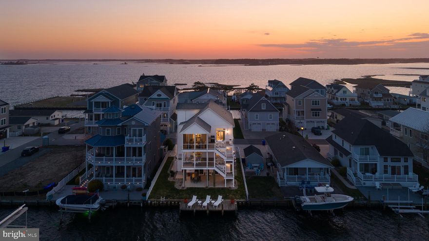 Welcome home to 38851 Grant Ave — a stunning canal-front masterpiece moments from Delaware's most scenic beaches near Fenwick Island. While others wait on permits, punch lists, and construction timelines, this move-in ready coastal gem is available right now. No waiting. No dust. No delays. Just pure, polished waterfront living — with a private dock, deep-water access to the Assawoman Bay, and a maritime lifestyle starting day one. This exceptional seven-bedroom + den, three full and two half-bathroom residence spans nearly 4,500 square feet across four thoughtfully designed floors. Only four years young, it lives and feels brand new — without the often overlooked new construction upgrades like custom closets and $12,000 worth of custom window coverings that are already installed in this home. An inverted floor plan maximizes views at every turn. Take the elevator to the third floor and prepare to have your breath stolen — a bespoke, magazine-worthy designer kitchen anchors the living and dining spaces, featuring Crystal cabinetry, quartz surfaces, a Thermador and GE Monogram appliance package, and clever kick-toe drawers that keep everything effortlessly organized. Just past the kitchen, a custom built-in bar commands attention: leathered marble, custom millwork, and a curated Marvel chiller suite — mini fridge, 100-bottle wine fridge, and a continuous ice maker — because your guests deserve better than lukewarm rosé. These spaces flow seamlessly to a large screened and covered porch with custom vinyl inserts for year-round use, ceiling fans, and sweeping canal views that make every evening feel like a getaway. The primary suite occupies its own wing on this level, offering an oversized bedroom, custom walk-in closet, designer bath, and sliding glass doors opening to a private canal-view deck. A linear fireplace anchors the living room, with a private office and powder room tucked neatly around the corner. The second floor hosts four secondary bedrooms, two full baths, a den perfect for an office, and a generous outdoor deck. The top floor flex space — ideal as a seventh bedroom or bonus room — opens to a rooftop deck with breathtaking bay views. On the ground floor, an insulated two-car garage with game room space rounds out one of the most versatile floor plans on the Delaware coast. Outside you will find a lush, but manageable, yard, large covered patio space, outdoor shower and a dock that has electricity – perfect for sunbathing or watersports – providing access to the deep waters of Assawoman Bay. Built with structural substance to match its style: 47 pilings, a four-story fire suppression sprinkler system, maintenance-free siding, composite decking, and VertiCable railings — structural details that protect your investment for decades. Minutes from Fenwick Island State Park, world-class dining, boutique shopping, and the beloved Freeman Stage outdoor concert venue. The Cape Windsor community adds a pool, tot lot, and picnic area. This is Coastal Delaware living at its absolute finest. Call it yours today — no waiting required.