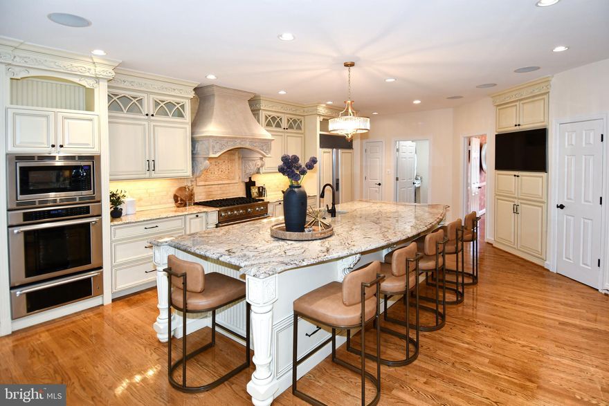 Welcome to 4007 Wintersweet Court in the sought-after Preserve at Smalls Nursery community in Rockville, MD. This impressive Craftmark Homes, Kenwood model offers 6 bedrooms, 5.5 bathrooms, approximately 7,938 square feet of living space on a .44-acre lot. From the moment you arrive, the home makes a stunning impression with Calvert stone walls on each side as you enter the driveway with lantern lights, custom stone mailbox, and front exterior lighting, highlighting the beautiful stone front, brick garage side, and vinyl siding exterior. The home has been freshly painted throughout.
Step inside to a welcoming foyer featuring a beautiful spiral staircase that leads into the heart of the home. The grand family room offers soaring ceilings and a striking stone gas fireplace, creating the perfect gathering space. The main level also includes a formal living room, elegant dining room, sunroom filled with natural light, and a private office with custom built-in shelving.
The gourmet kitchen is designed for both everyday living and entertaining, featuring a Viking gas cooktop, gorgeous custom hood, double Thermador wall ovens, warming drawer, built-in microwave, and a Sub-Zero refrigerator with custom wood panels matching the cabinetry. A large center island easily seats six stools, complemented by a separate table area for casual dining. The kitchen also includes a butler’s pantry with shelving and a wine refrigerator for added storage and entertaining convenience. Just off the kitchen is a winterized porch with heat and air conditioning, perfect for year-round enjoyment. The fully finished walk-out basement provides additional living space and features a dedicated wine cellar, along with plenty of room for recreation, guests, or a home gym. The owner’s suite is a true retreat, offering his and her closets and a private sitting room with custom built-ins and a charming window seat. The spa-like owner’s bath includes a separate soaking tub, spacious shower, and two separate sink areas. Outdoor living is just as inviting with a Trex deck and a beautiful flagstone patio with a built-in seating wall, perfect for relaxing or entertaining, all within a fully fenced backyard. Residents enjoy walking trails and a playground just steps away, with convenient access to ICC (MD-200), the Rockville Metro (approximately 6–7 miles away), shopping, dining, and parks.