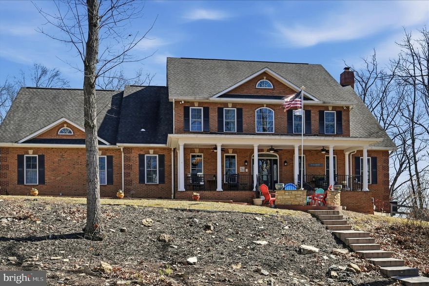 NO HOA! Set on 4.33 private wooded acres in Leesburg Country Club, this custom four-sided brick Colonial offers 4 bedrooms, 3.5 baths, and over 5,400 finished square feet just minutes from Historic Downtown Leesburg. A welcoming full front porch and dramatic two-story foyer with a striking floating staircase set the tone for the home’s warm, elegant interior. Brazilian cherry hardwoods span the main level, where formal living and dining rooms flow into a spacious family room with fireplace. The remodeled kitchen features granite countertops, abundant cabinetry, stainless steel appliances, double wall ovens, a walk-in pantry, and an oversized island. Upstairs, the expansive primary suite offers a spa-like bath and private balcony retreat. The walk-out lower level provides exceptional flexibility with a large rec/game room, bar area, full bath, and a private den ideal for a home office. Outdoor living includes two rear balconies, a pergola-covered patio, and a partially fenced rear yard surrounded by mature trees for exceptional privacy. You will experience dramatic panoramic views of the area as this home is at the highest peak in Leesburg! Major updates include the kitchen and main-level bath in 2021, plus HVAC, furnace, and heat pump in 2018.