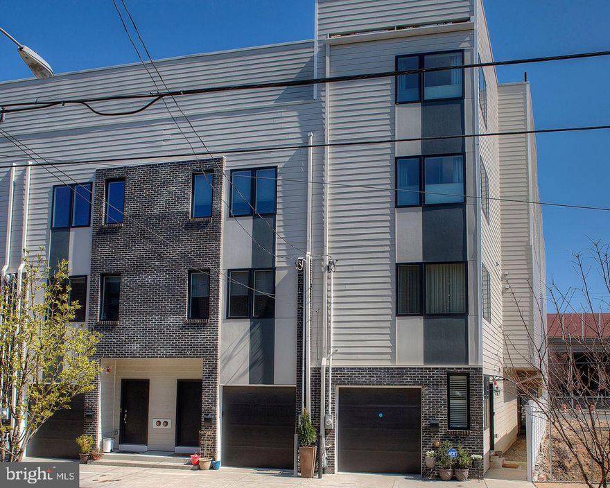 Welcome to "Penns Point" and the largest end unit in the development with a full 5 years left on the tax abatement. This home was professionally redesigned with substantial upgrades, post purchase by Archer Buchanan Architects to maximize every square inch of space and thus turning into a showcase of comfort and design for today's modern living. The extra wide home features a luxurious floor through primary suite, 4 additional bedrooms, 3 full and 1 half baths, oversized corner windows, a live rooftop garden, finished basement, gleaming oak hardwood floors, dual zoned HVAC, garage parking and an elevator that goes from the first floor to 4th. The side entrance welcomes you into a spacious foyer with access to the garage and guest bedroom with ensuite bath. Below is a finished basement featuring a family room with engineered hardwood floors and a large window and unfinished storage area with mechanicals.  Back up to the foyer via the center staircase takes you to the main living area where the home stretches out to 24' wide. The kitchen features cherry cabinetry, GE Profile stainless appliances and Silas stone counters. The dining room is adjacent with access to the rear deck with custom awning. The sun filled living room completes the 2nd level. The third level features 3 additional bedrooms (currently being used as 2 offices and a gym) and a full hall bath with tub/shower and cream-colored tile. The 4th floor primary suite is a dream with oak hardwood floors, an oversized bath with soaking tub, large, tiled shower, separate WC and large linen closet, a fabulous oversized "she" closet, a full-sized laundry room, breakfast bar and another walk-in "his" closet. The main bedroom is flooded with sunlight and the best sunsets through the corner double window. The last stop on this tour is the sensational rooftop complete with custom awning and a live garden to delight throughout all the seasons. Full city and bridge views are all yours.