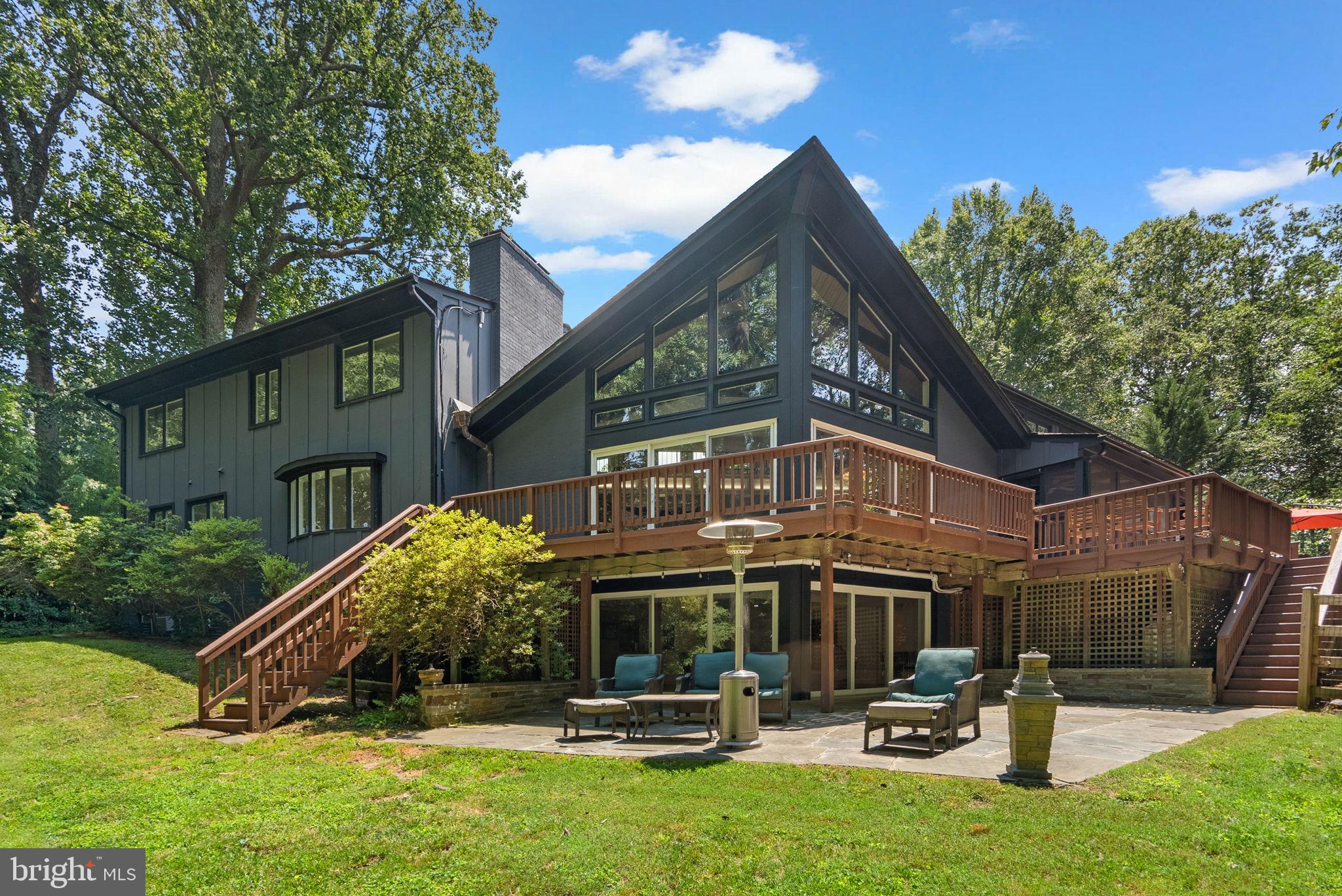 Stunning Renovated Contemporary Retreat in Prime Potomac Location! Tucked away on a private, partially fenced, wooded 2.74-acre lot in the highly desirable Potomac Manor community, this beautifully renovated contemporary residence seamlessly blends striking modern architecture with tranquil natural surroundings—just minutes from the shops and dining of Potomac Village Shopping Center.
A dramatic double-door entry opens into a soaring Great Room featuring vaulted, beamed ceilings, expansive walls of glass, and oversized windows and sliders that flood the home with natural light and invite the outdoors in. The wrap-around deck provides a spectacular setting for enjoying peaceful woodland views year-round. Anchored by a floor-to-ceiling stacked stone fireplace, the Great Room sets the tone for elegant yet relaxed living.
Completely reimagined, the gourmet kitchen is outfitted with sleek Porcelanosa cabinetry and countertops, high-end appliances, and an oversized center island perfect for entertaining. A large picture window frames the front yard, while glass sliders connect seamlessly to the screened-in porch—an ideal space for dining, relaxing, or year-round gatherings.
The main level includes a serene primary suite retreat with dual closets (including a custom walk-in), a private laundry closet, and a luxurious spa-like bath with dual vanities and a tandem shower system. A flexible additional room on the main level—with its own wood-burning fireplace—makes an excellent home office or guest bedroom.
A sweeping spiral staircase leads to the upper-level catwalk overlooking the main living space. Upstairs, you’ll find five generously sized bedrooms with picturesque views and two beautifully updated bathrooms. An unfinished space offers the opportunity for expansion or additional storage.
The walk-out lower level features a spacious recreation room with a third fireplace and a dry bar—perfect for entertaining. Glass doors open to a slate patio and a backyard fire pit area, ideal for evening gatherings. This level also includes a versatile gym room, a bedroom, and a full bath.
Additional highlights include a newly installed Hardie Plank exterior, new flooring throughout, updated HVAC and water heater systems, a main-level mudroom with powder room and laundry, a two-car carport (Seller plans to convert the carport into a 2 car garage) with storage closets, and a circular driveway with ample guest parking.
This exceptional home offers a rare combination of modern design, privacy, and convenience—just a short drive to Potomac Village, top-rated schools, and commuter routes.